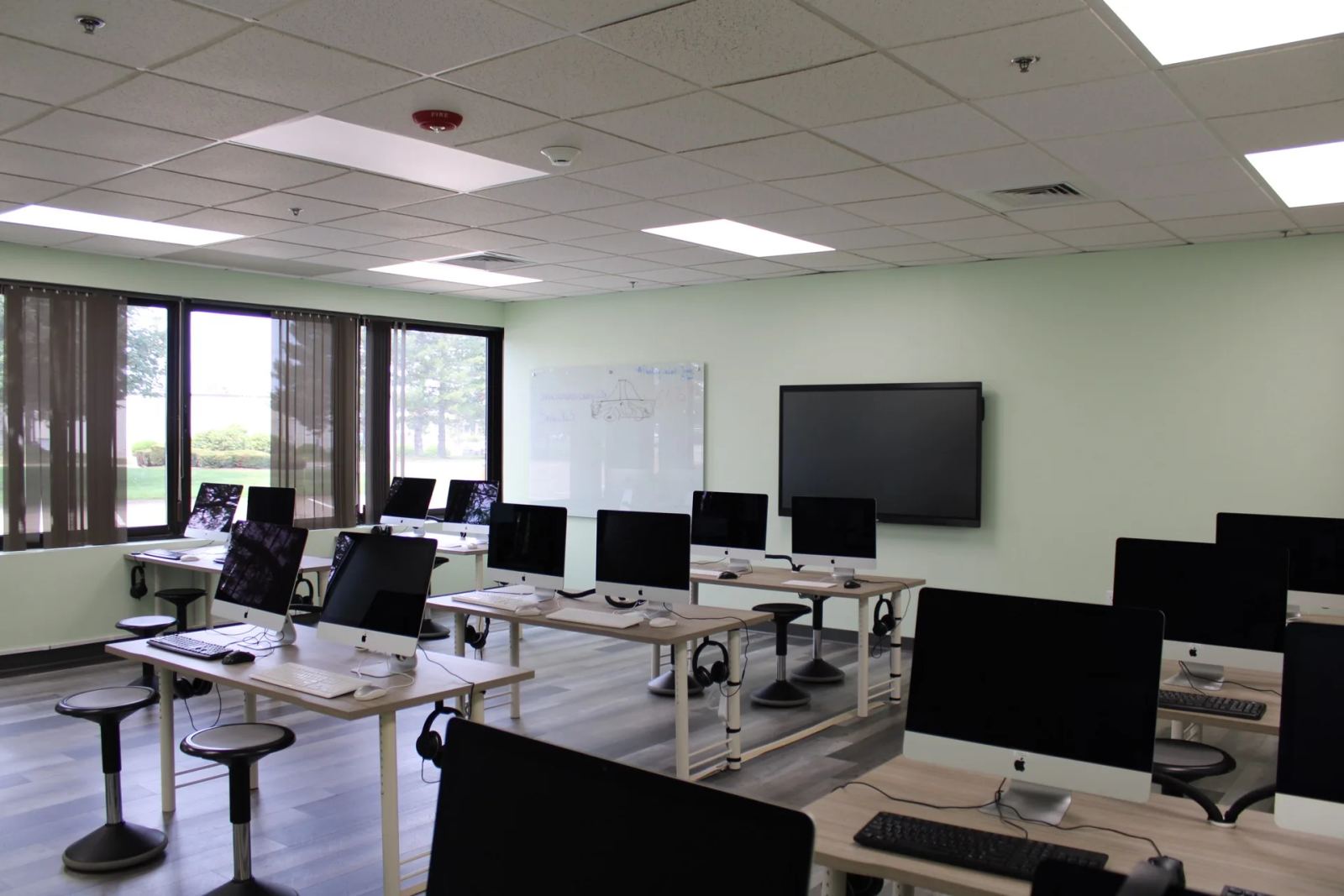 A technology lab at SELA's Hingham campus, with rows of iMac workstations and a large display screen.