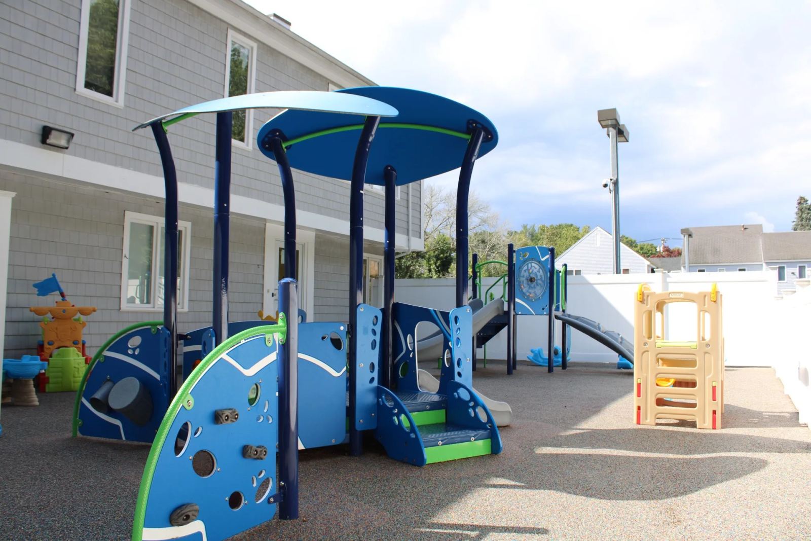 An outdoor playground at SELA's Norwell campus, with a blue-and-green climbing structure beside the building.