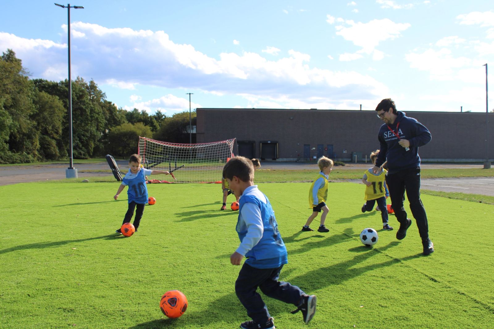 SELA students practicing soccer with their gym teacher on the mini soccer field