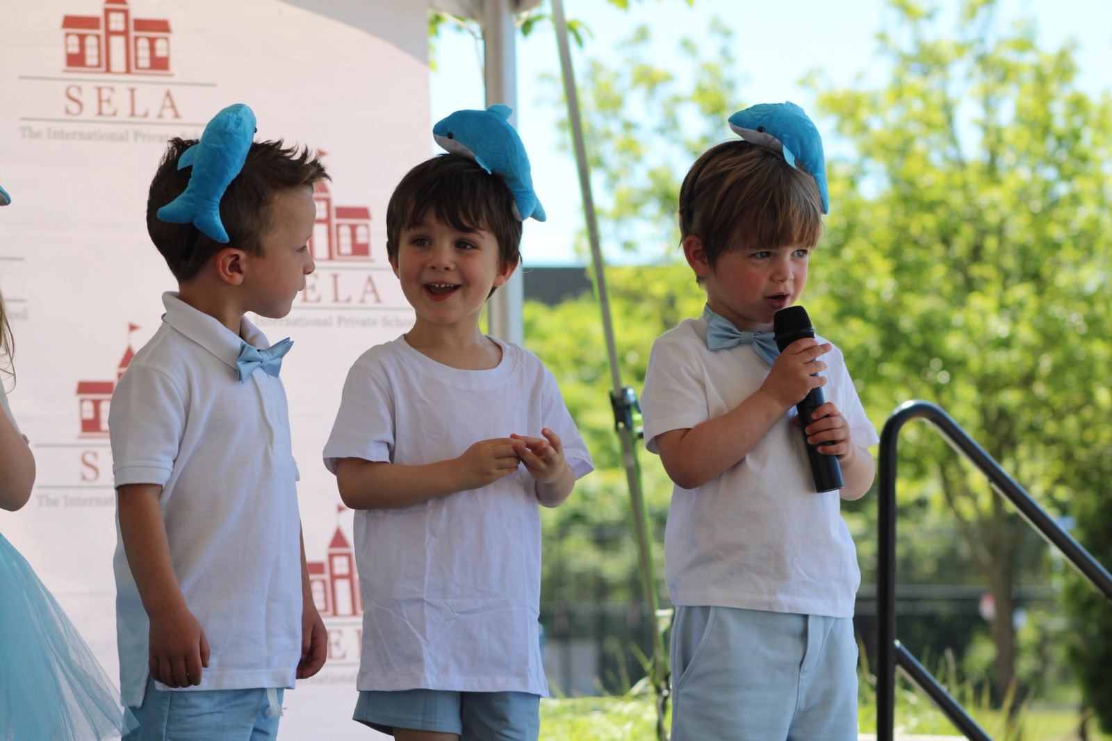 SELA students on stage speaking into the microphone