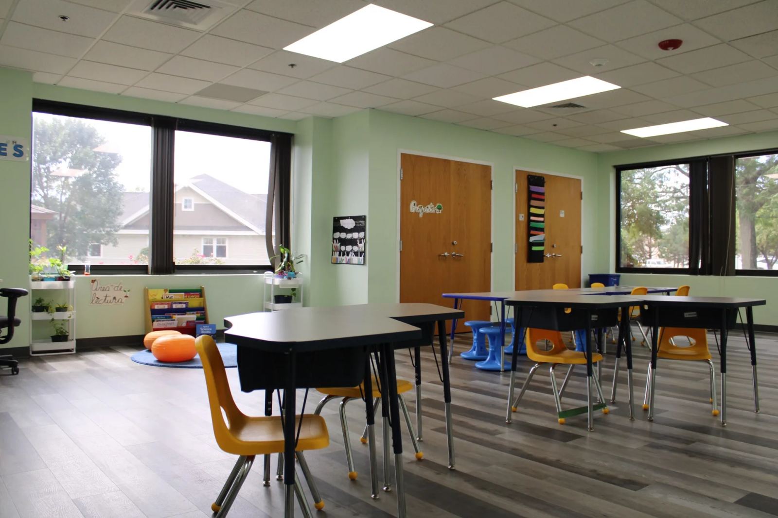 A sunlit Elementary classroom at SELA's Hingham campus, with a reading nook and tables beneath tall windows.
