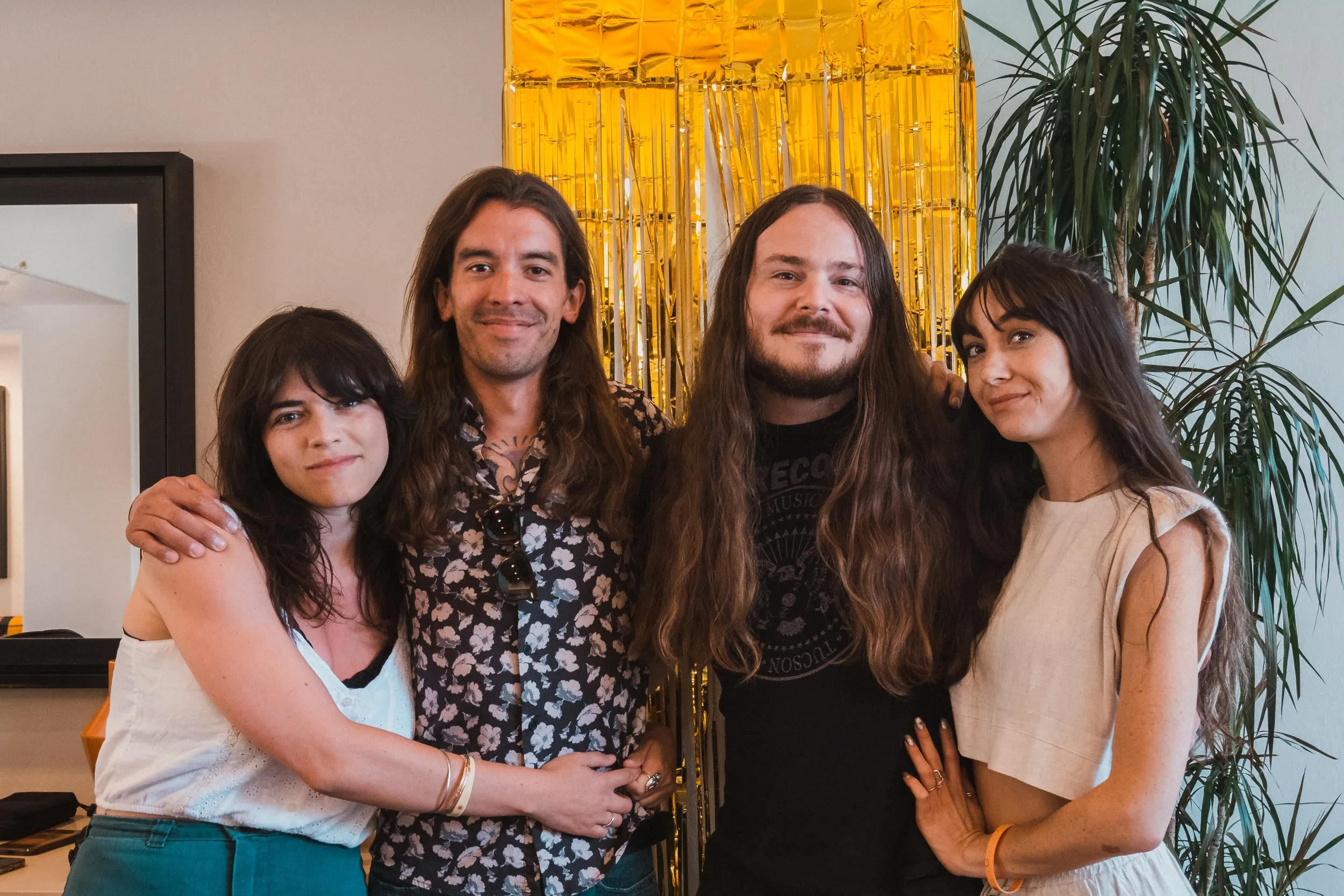 Friends posing together in front of a gold fringe curtain at a private celebration, Orange County.