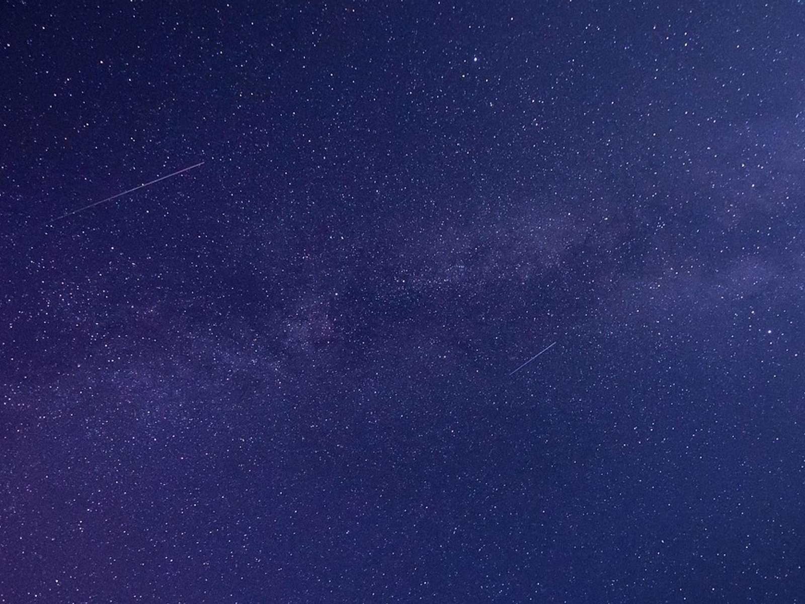 The Milky Way stretching across a dark blue starry night sky