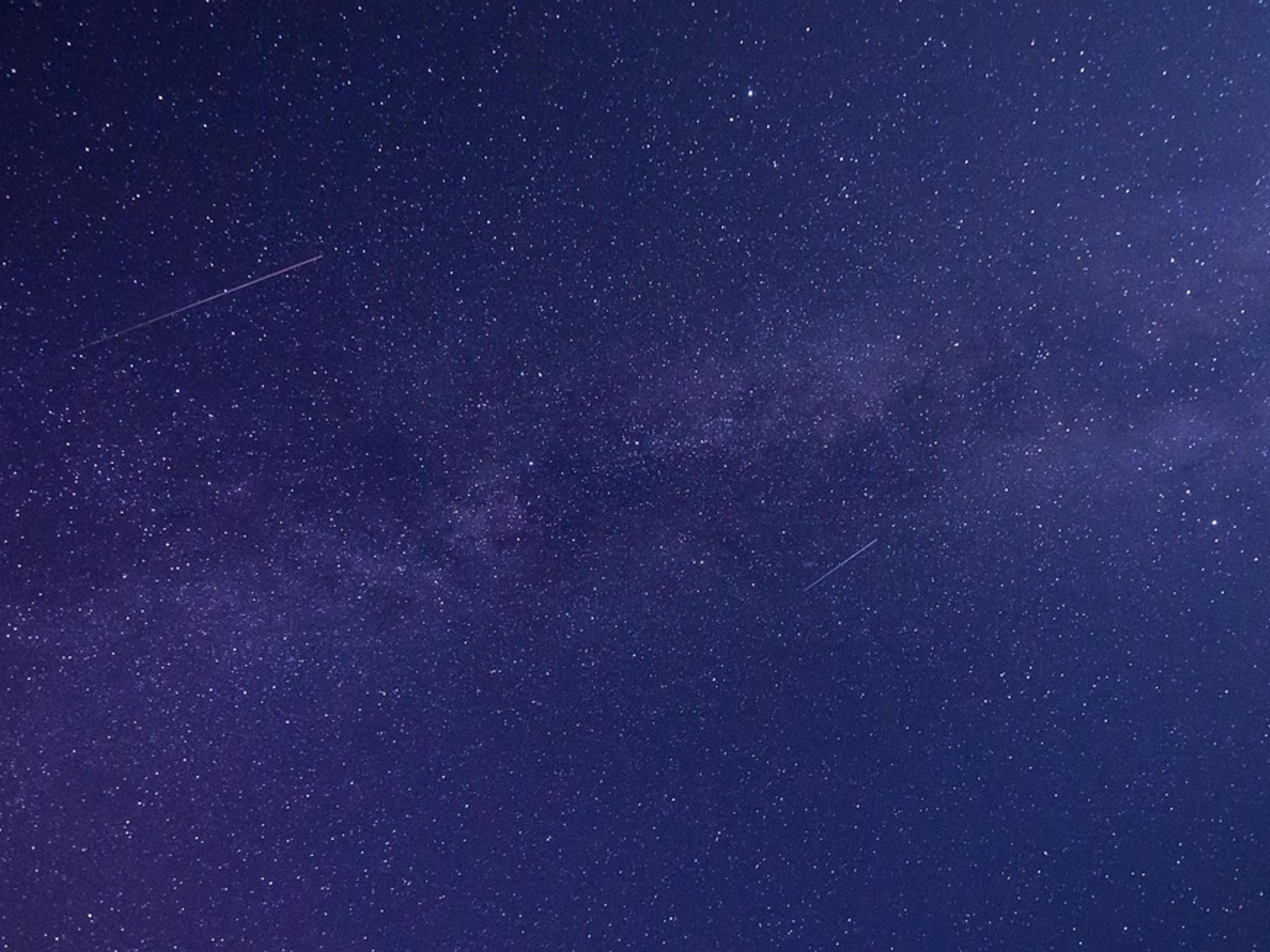 The Milky Way stretching across a dark blue starry night sky