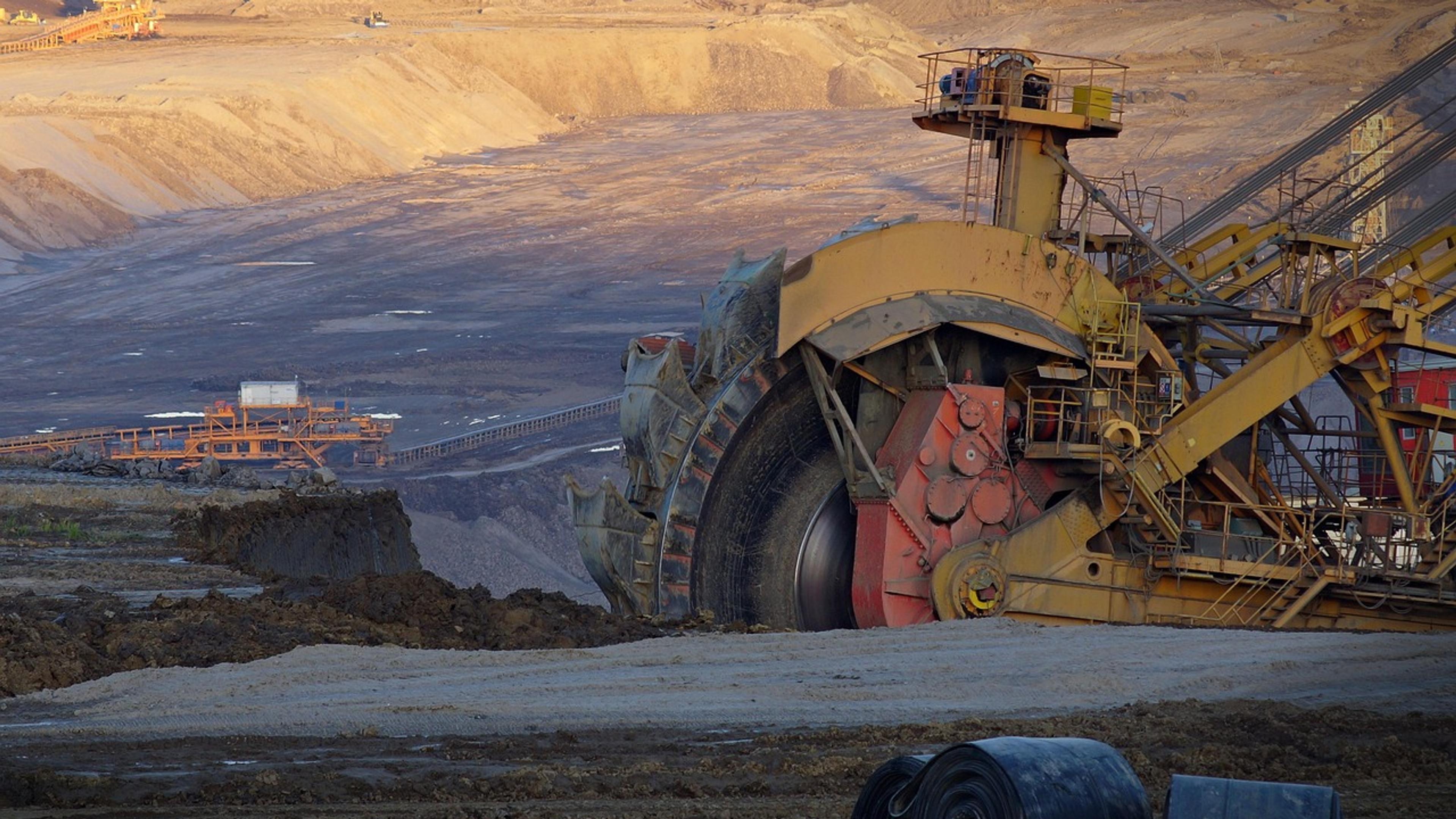 A large bucket-wheel excavator in an open-cut coal mine at dusk