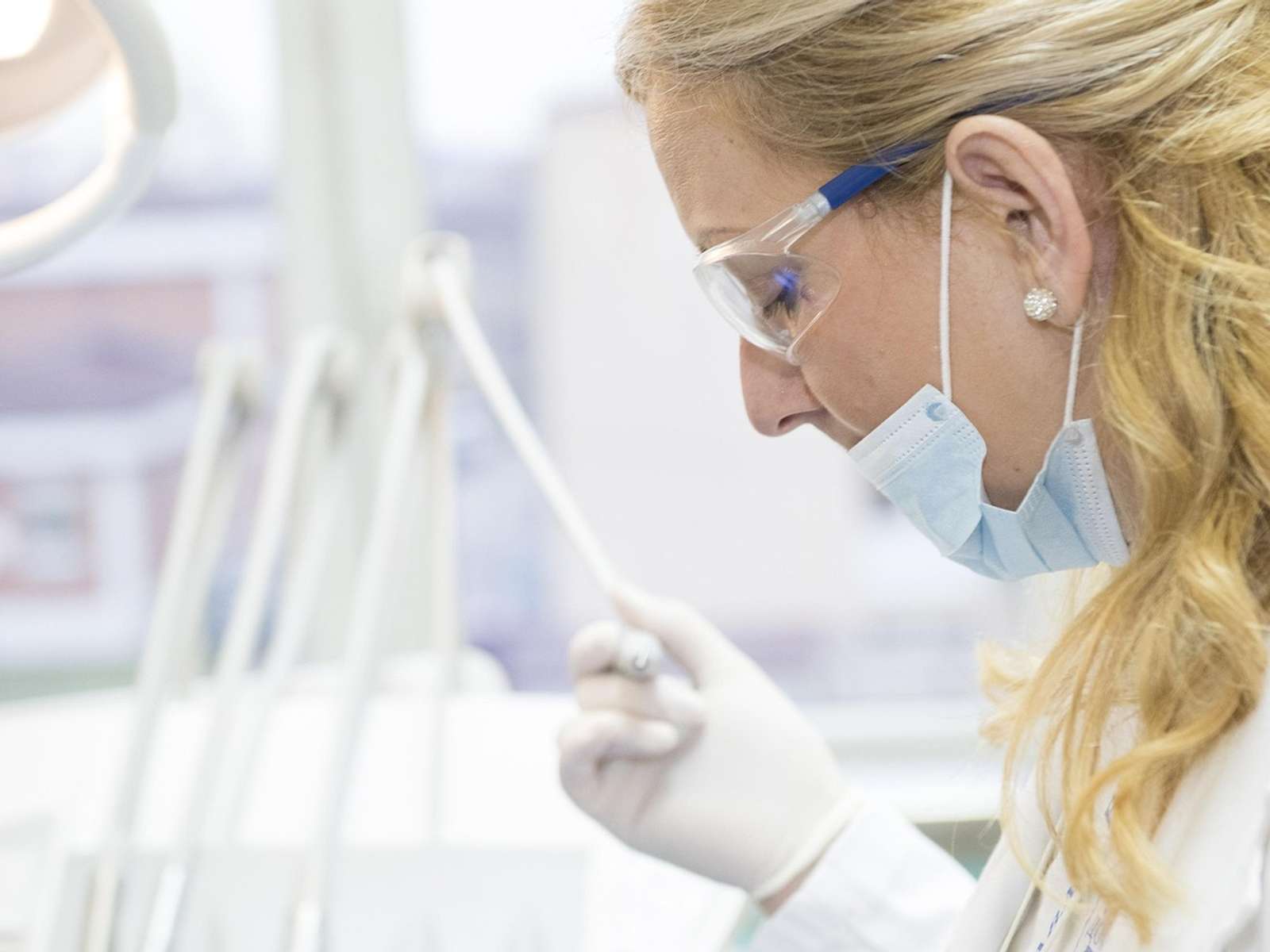 A researcher in gloves and a face mask examining a test tube in a laboratory