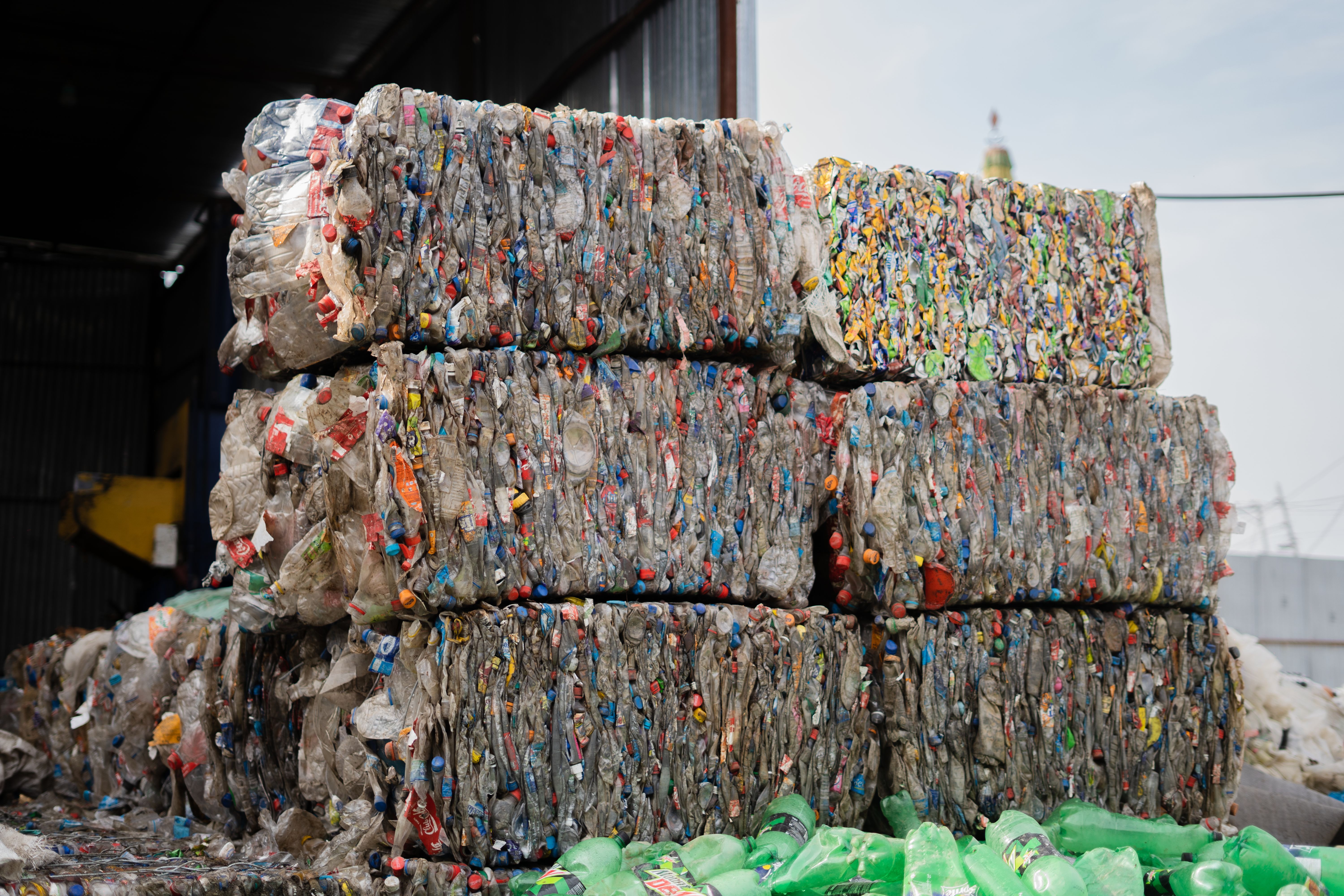 Stacked bales of compressed plastic bottles at a recycling facility, ready for processing
