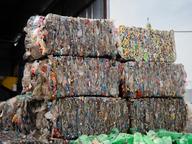 Stacked bales of compressed plastic bottles at a recycling facility, ready for processing