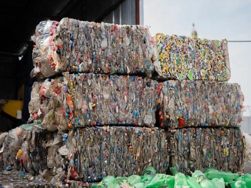 Stacked bales of compressed plastic bottles at a recycling facility, ready for processing