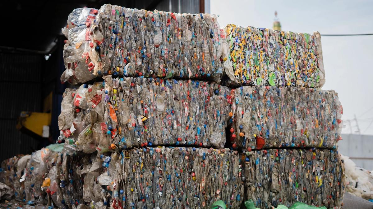 Stacked bales of compressed plastic bottles at a recycling facility, ready for processing
