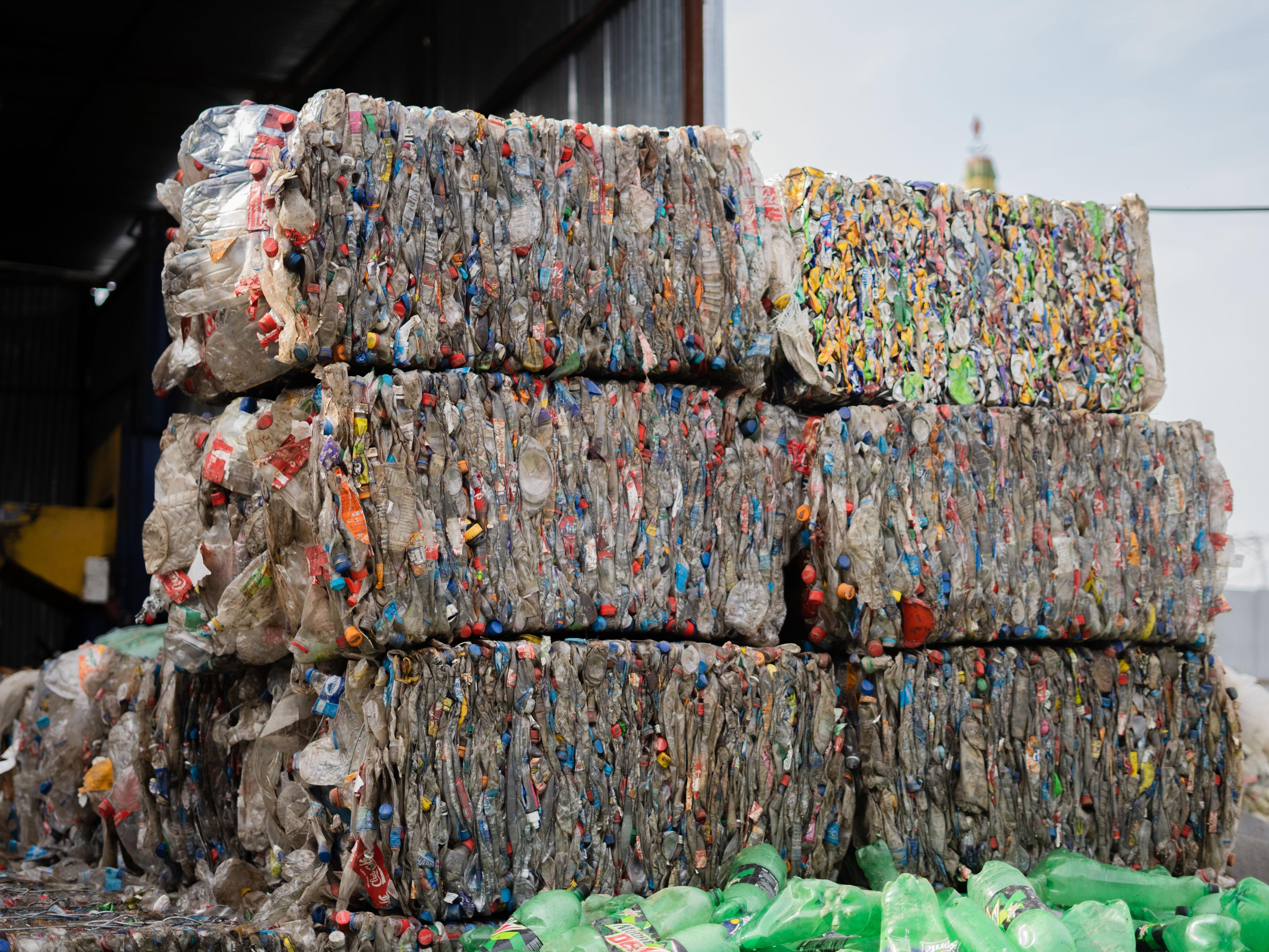 Stacked bales of compressed plastic bottles at a recycling facility, ready for processing