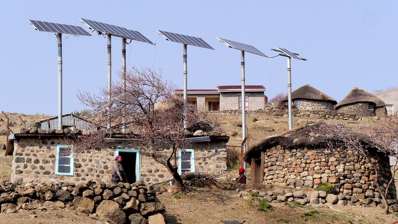 Solar panels on poles beside round stone houses in a mountain village in Lesotho