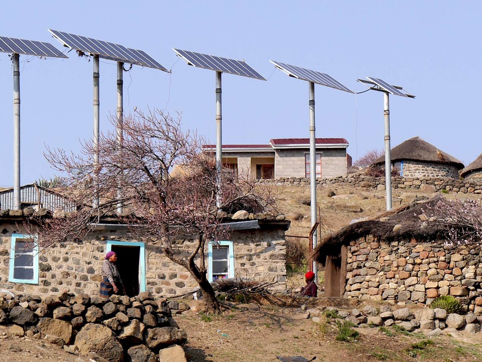 Solar panels on poles beside round stone houses in a mountain village in Lesotho