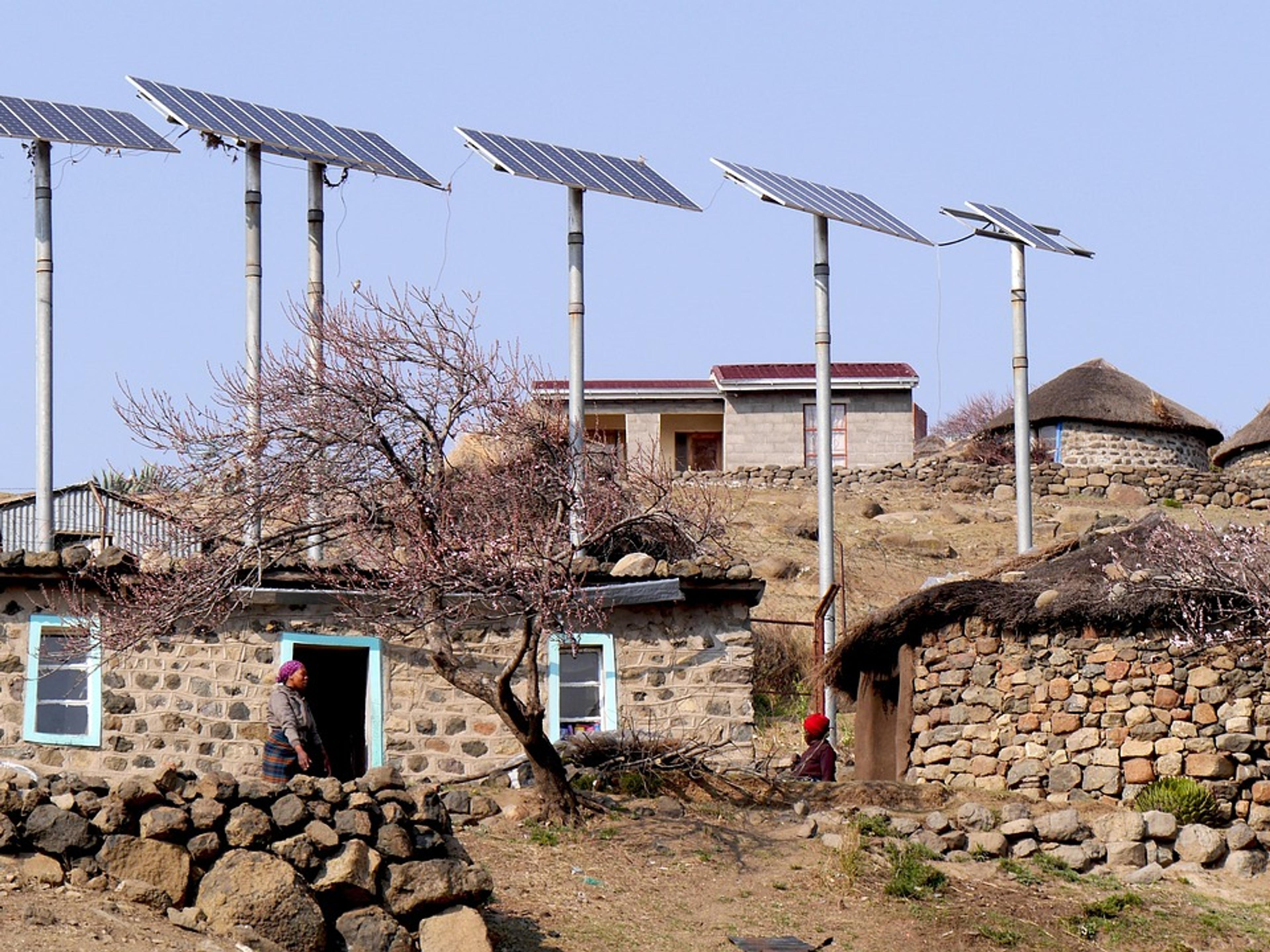 Solar panels on poles beside round stone houses in a mountain village in Lesotho