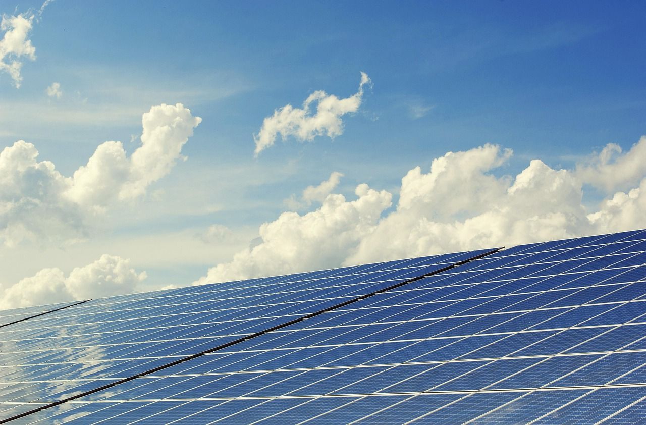 Solar panels angled toward a bright sky with white clouds