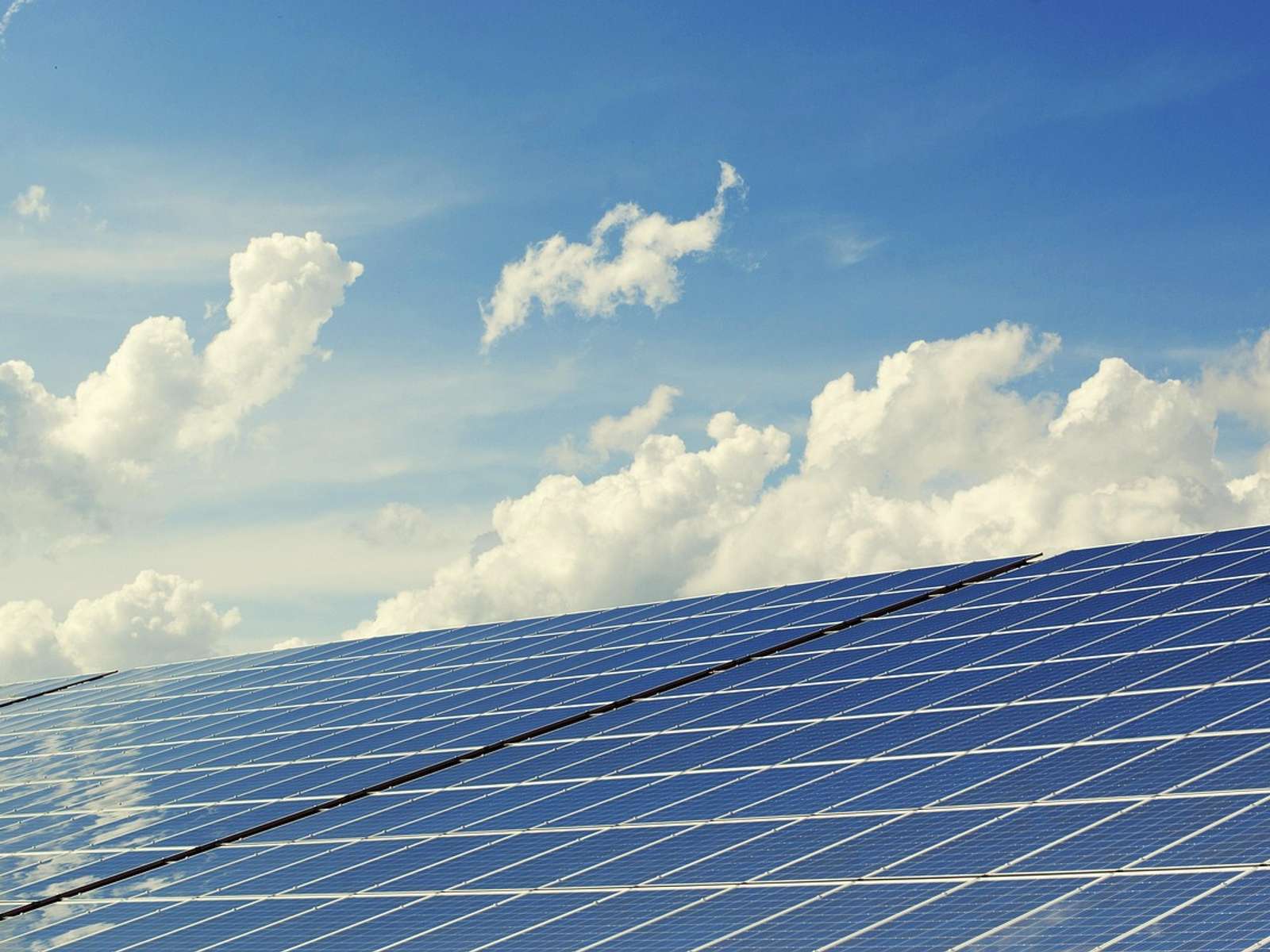Solar panels angled toward a bright sky with white clouds