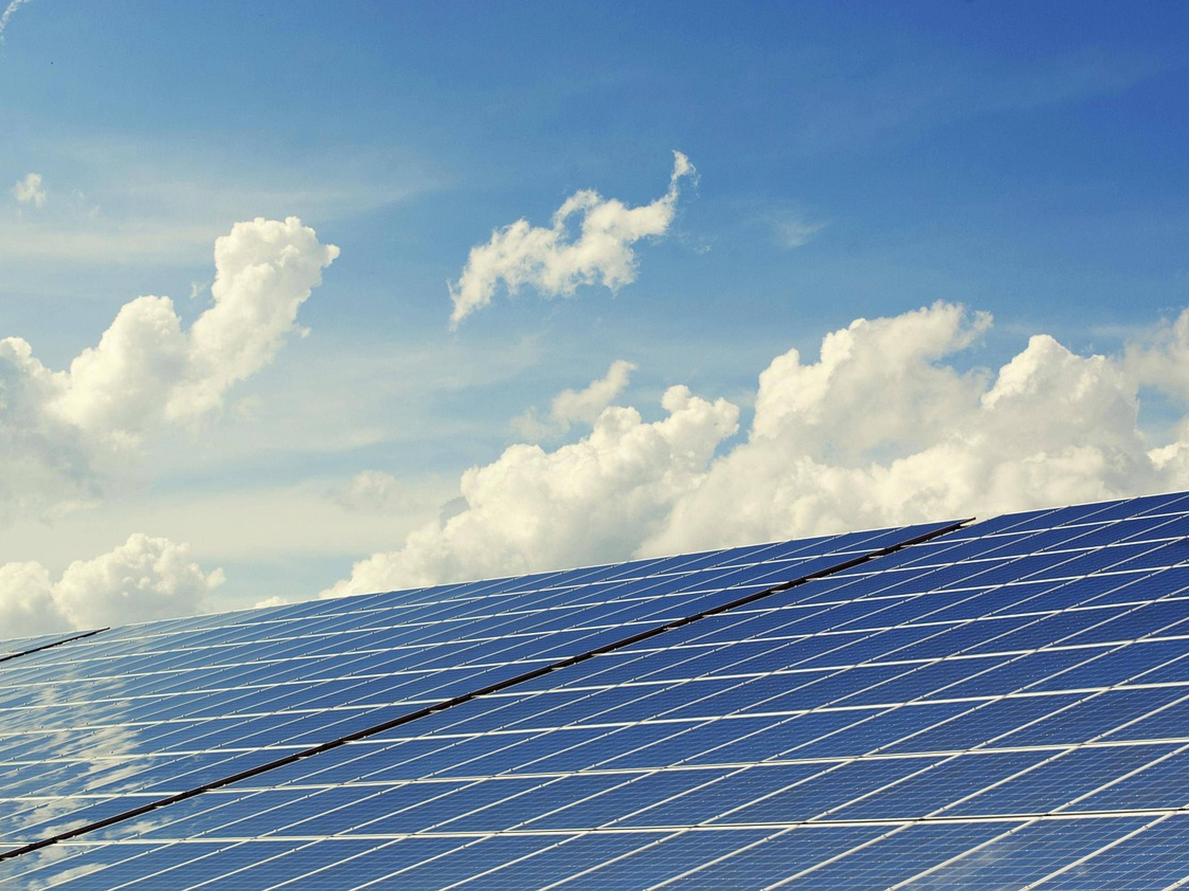 Solar panels angled toward a bright sky with white clouds
