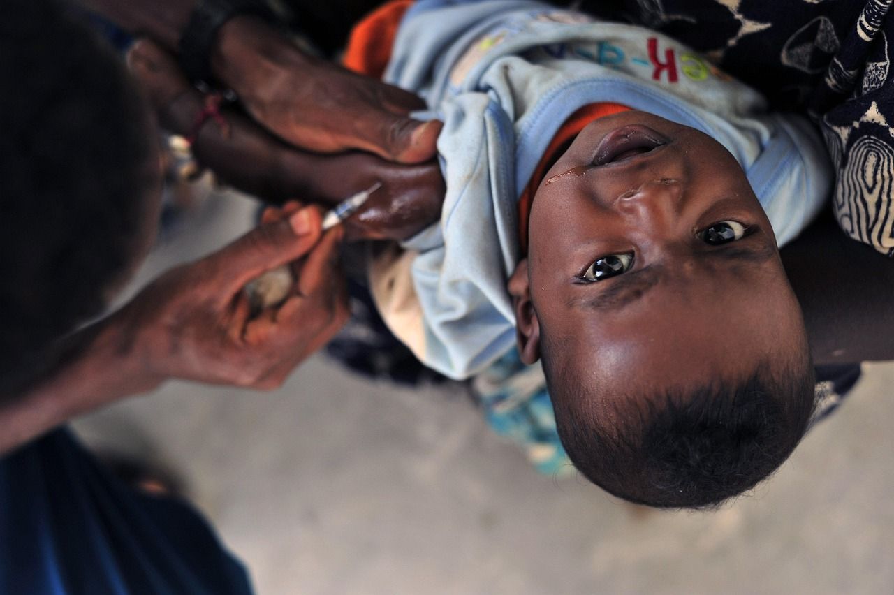 A health worker gives a young child an injection in the arm