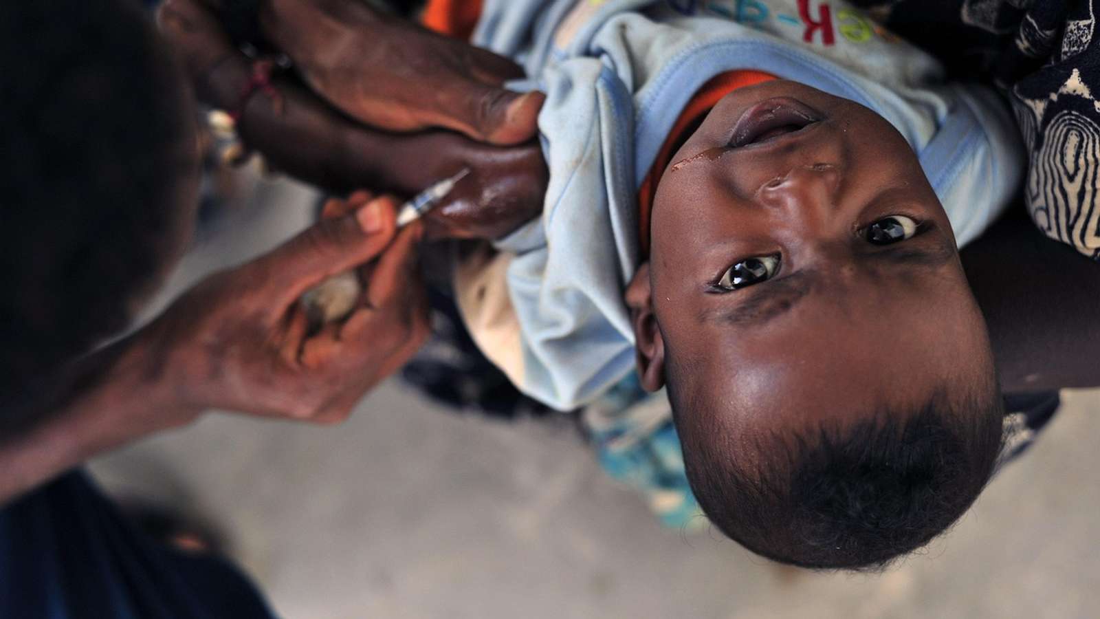 A health worker gives a young child an injection in the arm