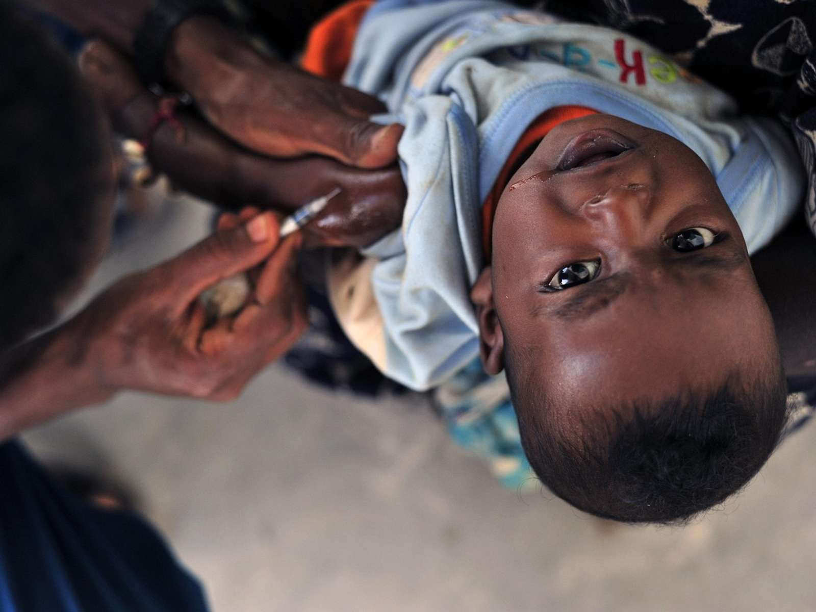 A health worker gives a young child an injection in the arm