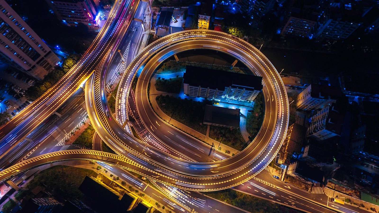 Aerial view of city streets and a roundabout lit up at night