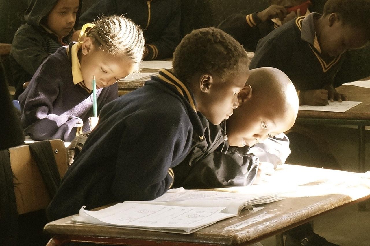 Students bent over their notebooks, writing at desks in a classroom