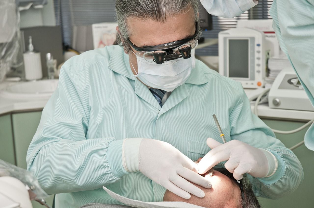 A dentist wearing magnifying loupes and gloves treating a patient