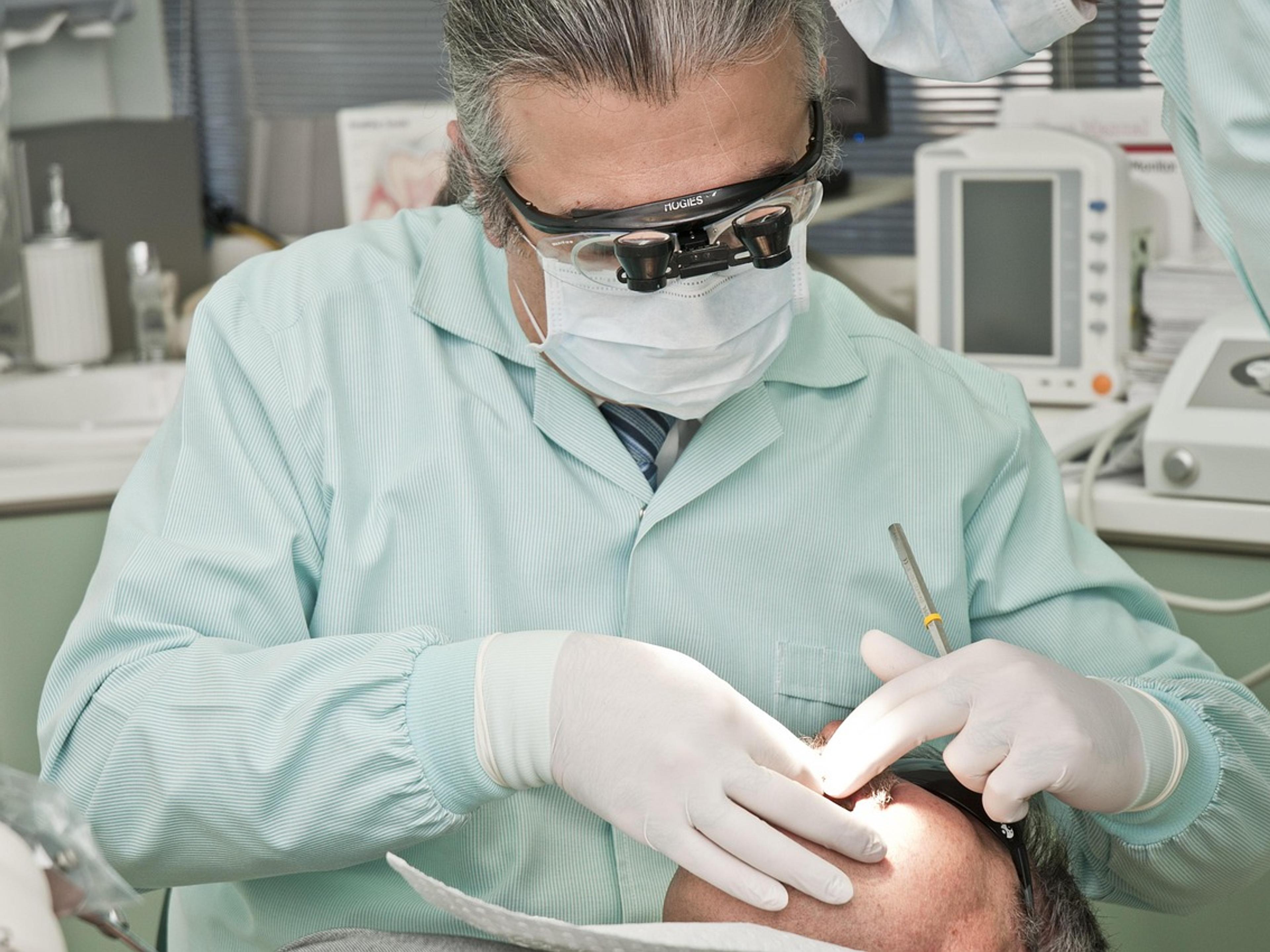 A dentist wearing magnifying loupes and gloves treating a patient