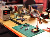 An electronics workbench with circuit boards, soldering tools, and precision instruments, representative of the prototyping work behind the new modular building blocks.