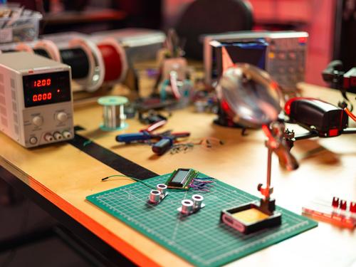 An electronics workbench with circuit boards, soldering tools, and precision instruments, representative of the prototyping work behind the new modular building blocks.