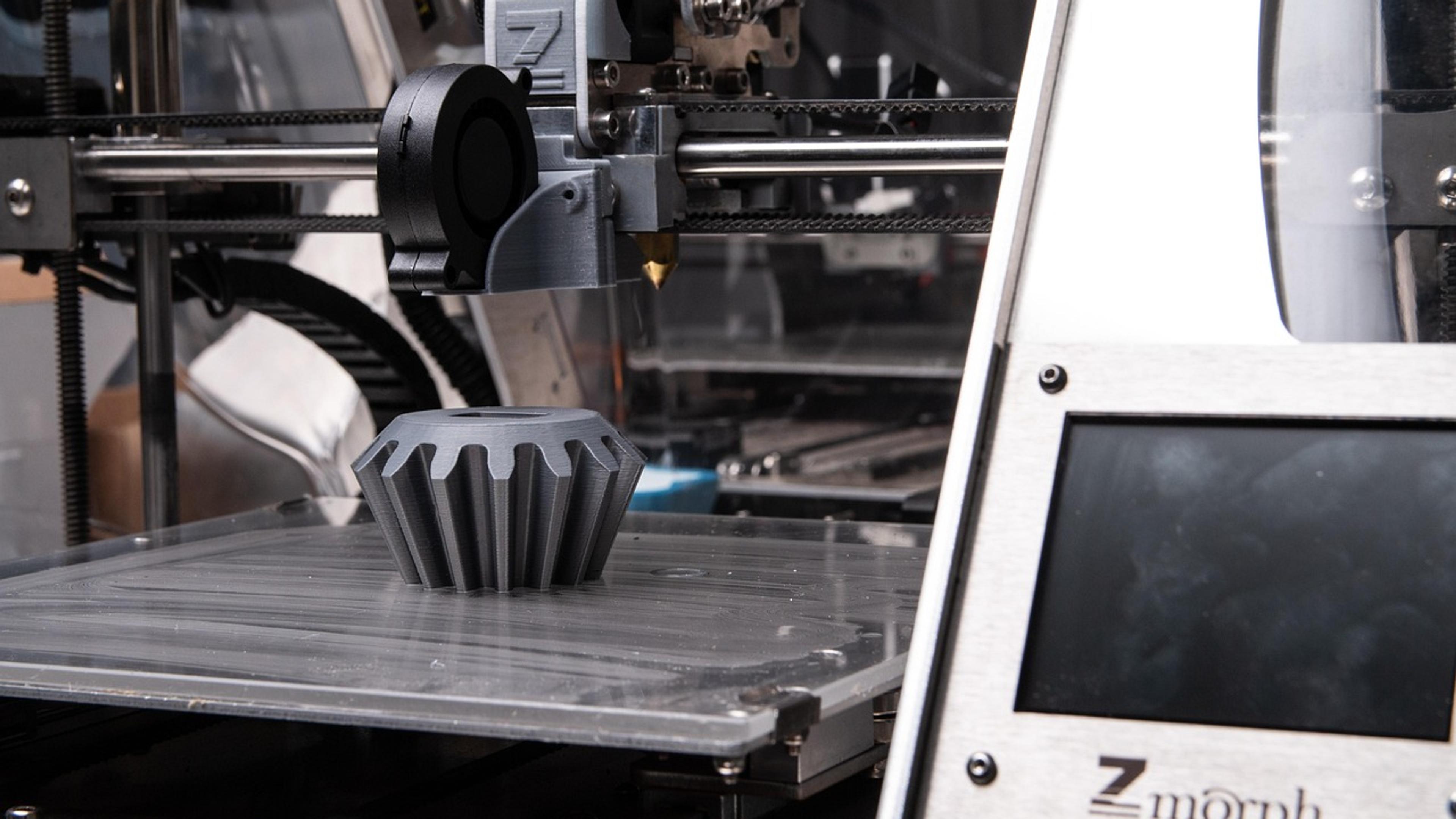 A 3D printer printing a dark plastic object