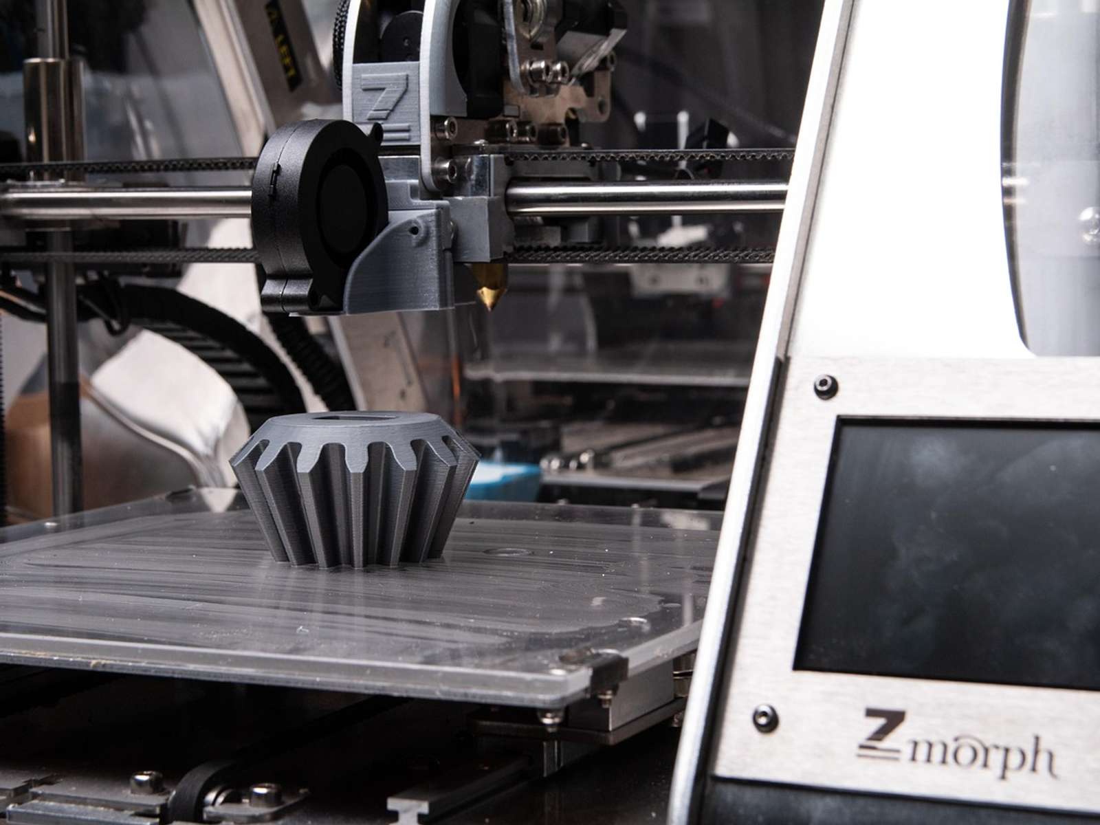 A 3D printer printing a dark plastic object