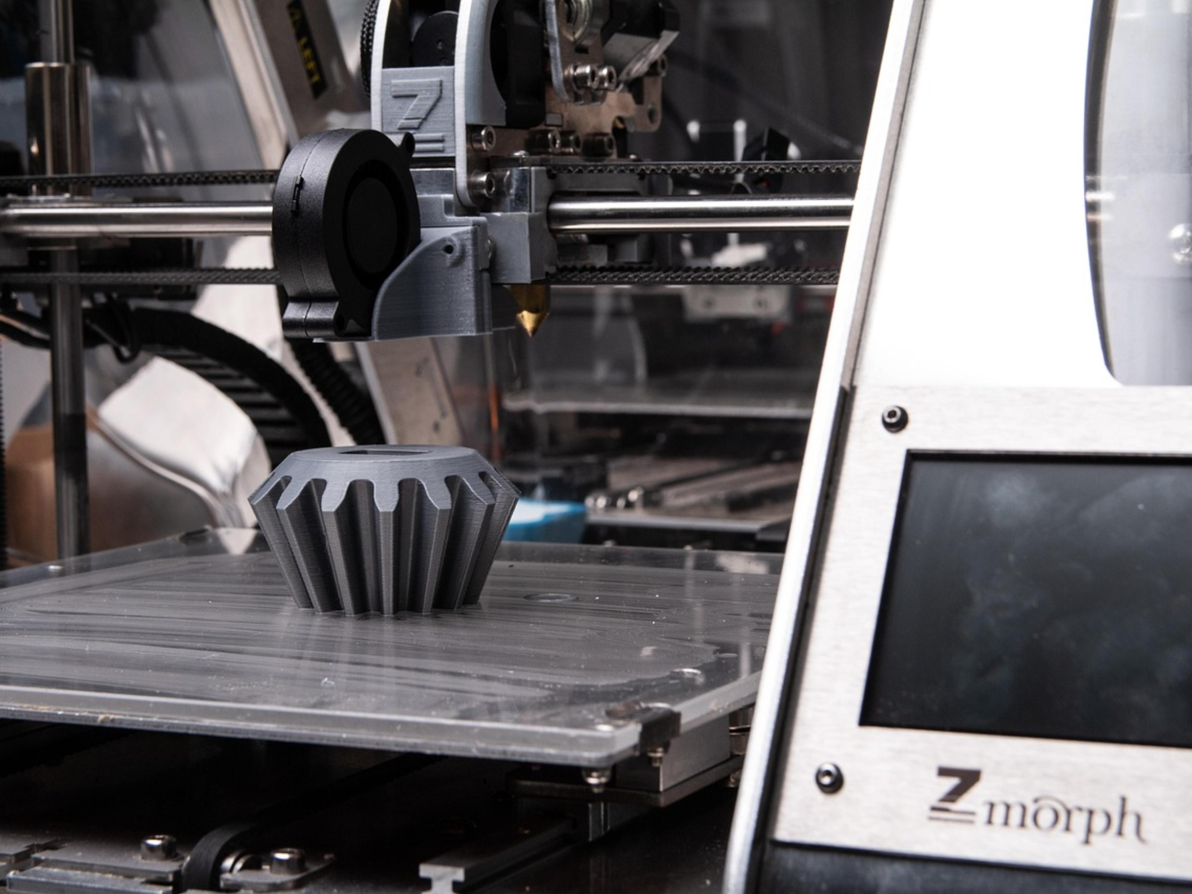 A 3D printer printing a dark plastic object