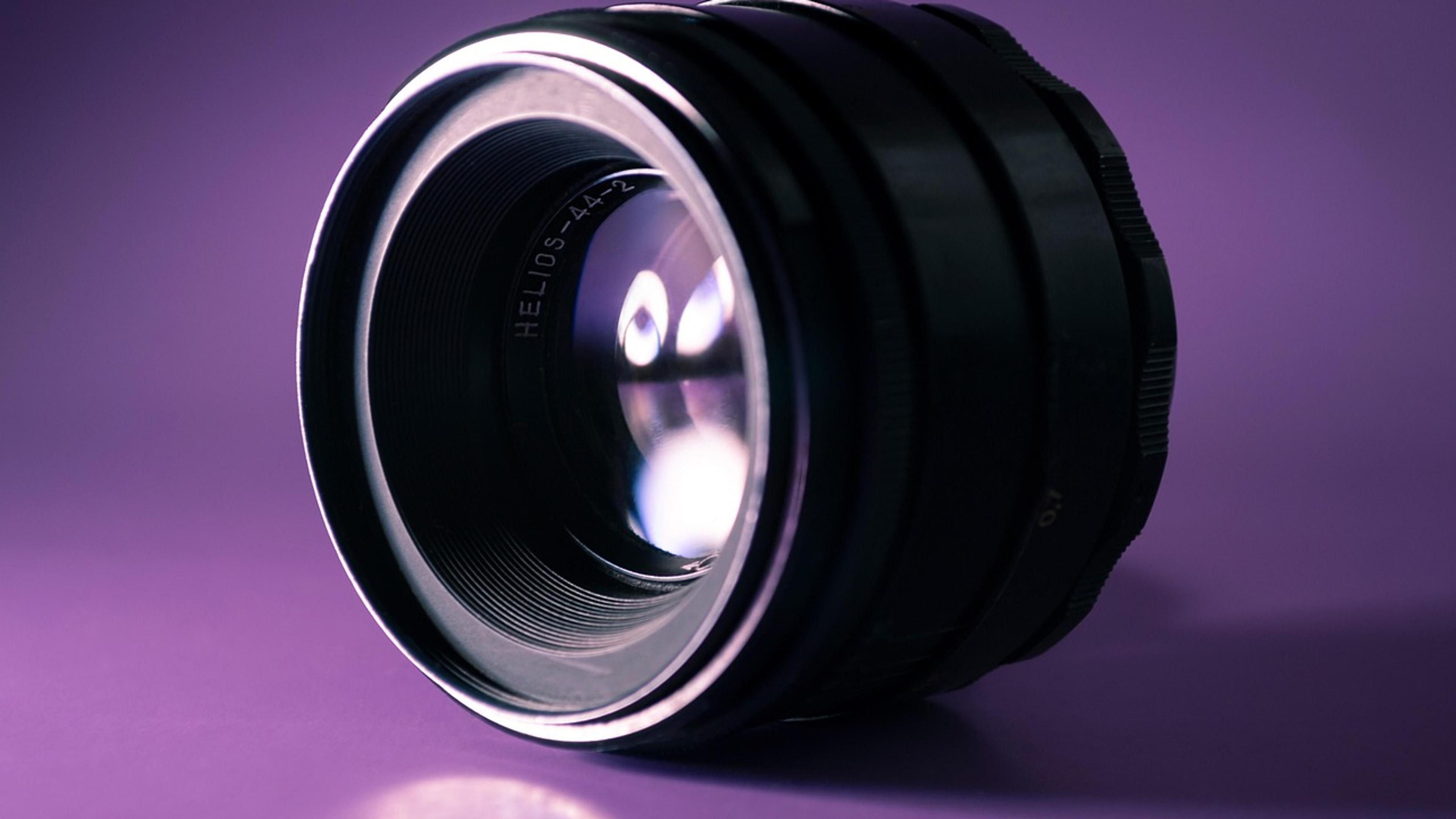 Close-up of a precision optical lens lit against a purple background