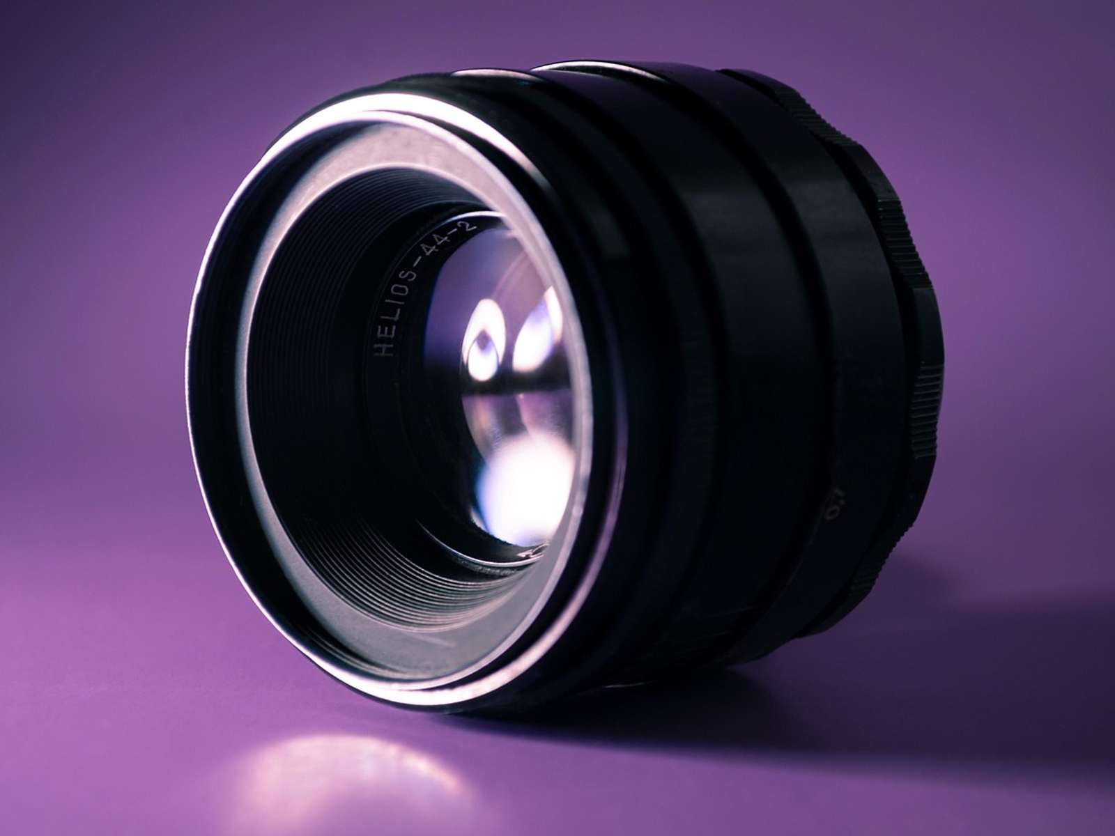 Close-up of a precision optical lens lit against a purple background