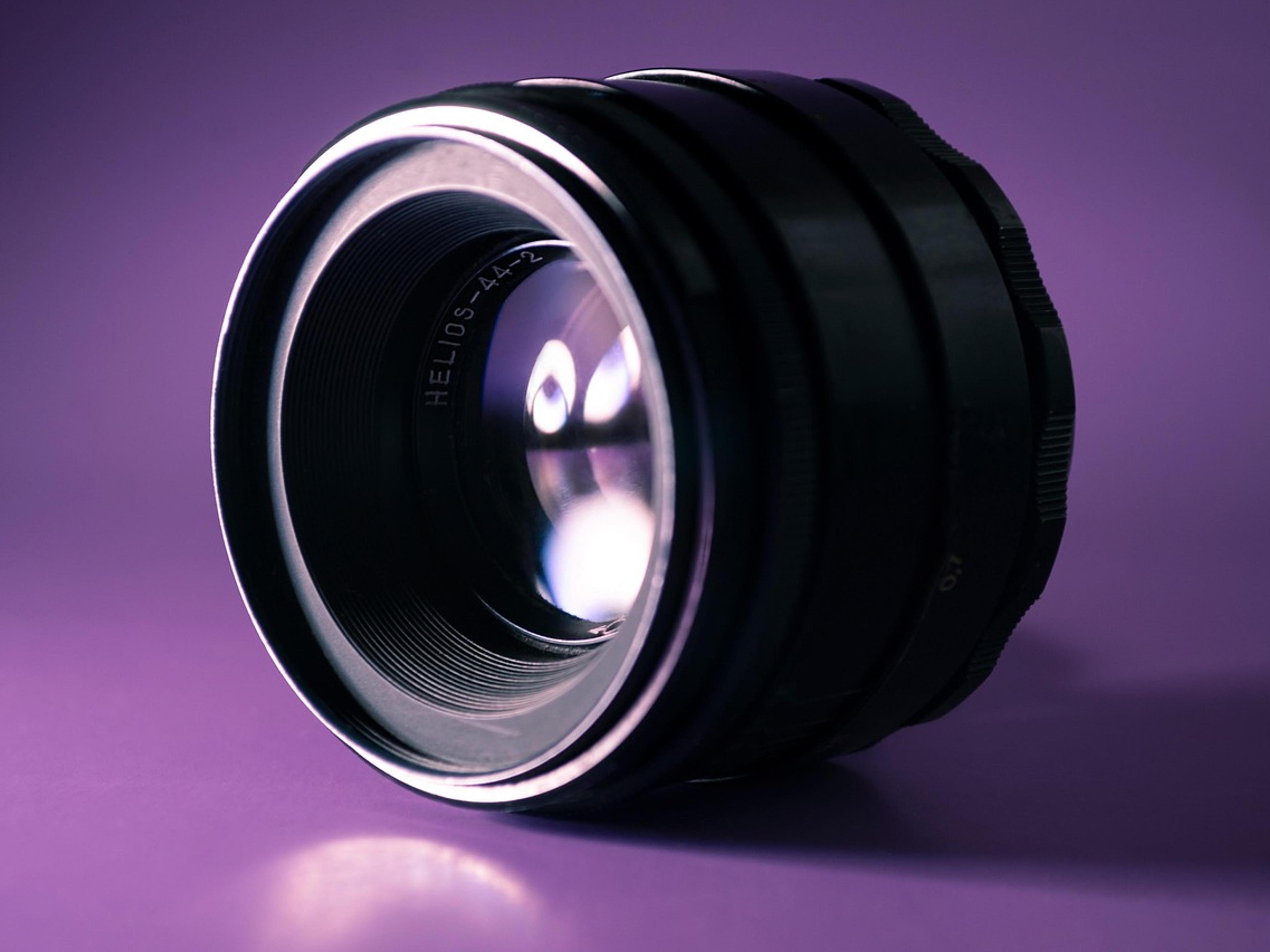Close-up of a precision optical lens lit against a purple background