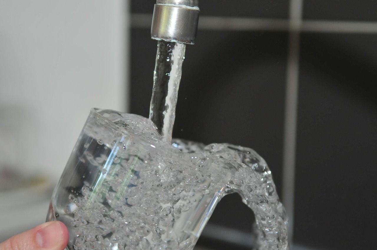 Clear water running from a kitchen faucet into a glass