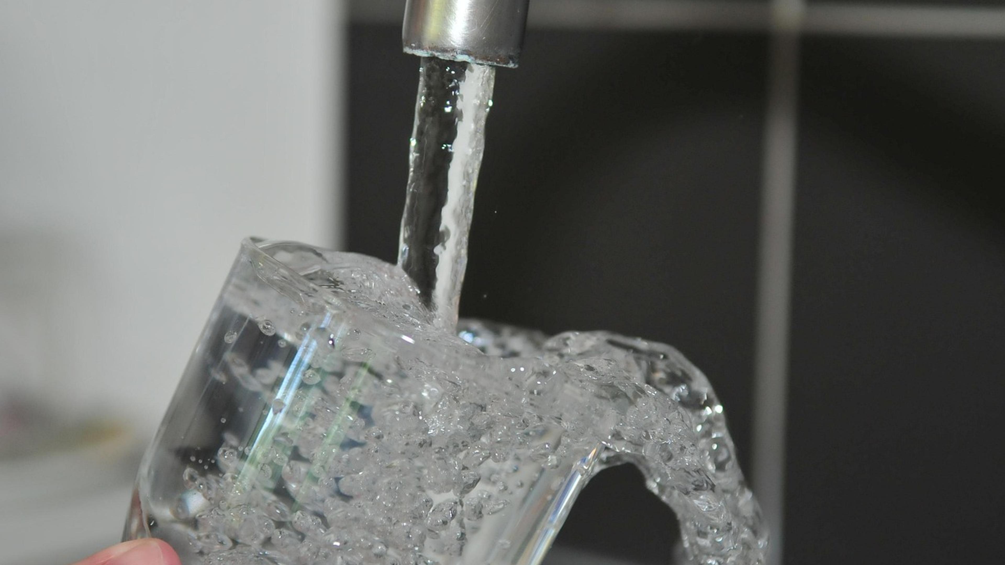 Clear water running from a kitchen faucet into a glass