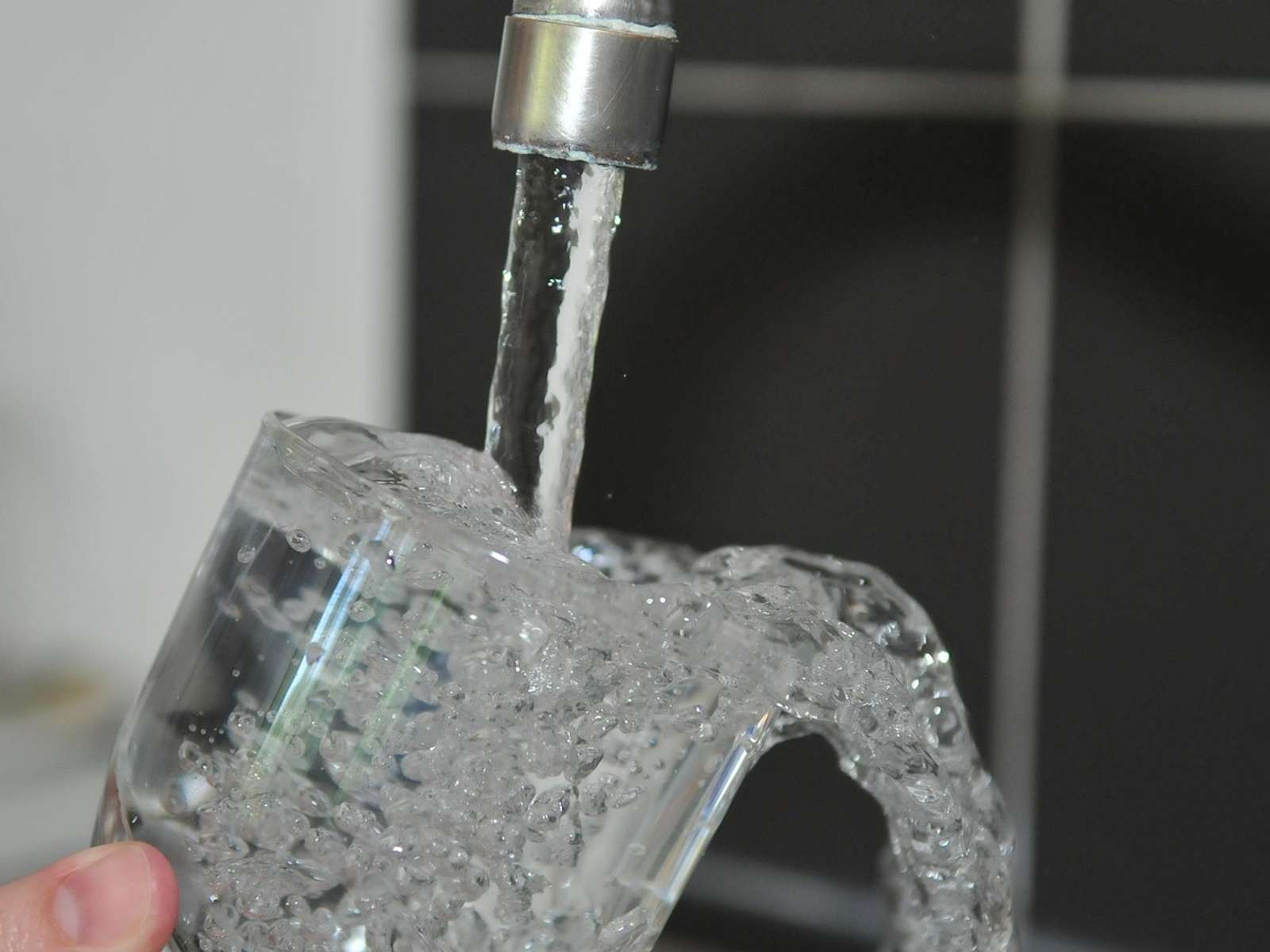 Clear water running from a kitchen faucet into a glass