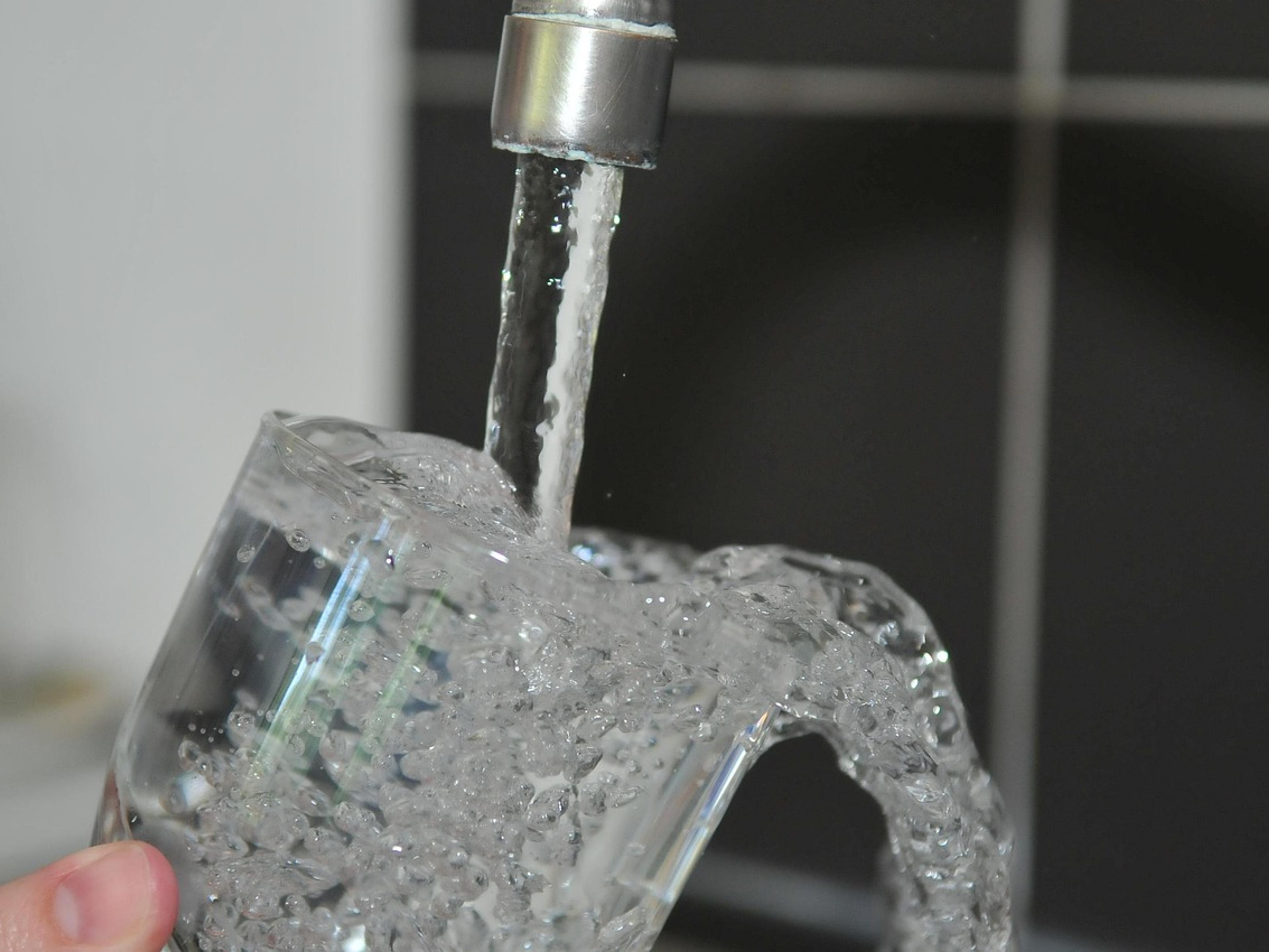 Clear water running from a kitchen faucet into a glass