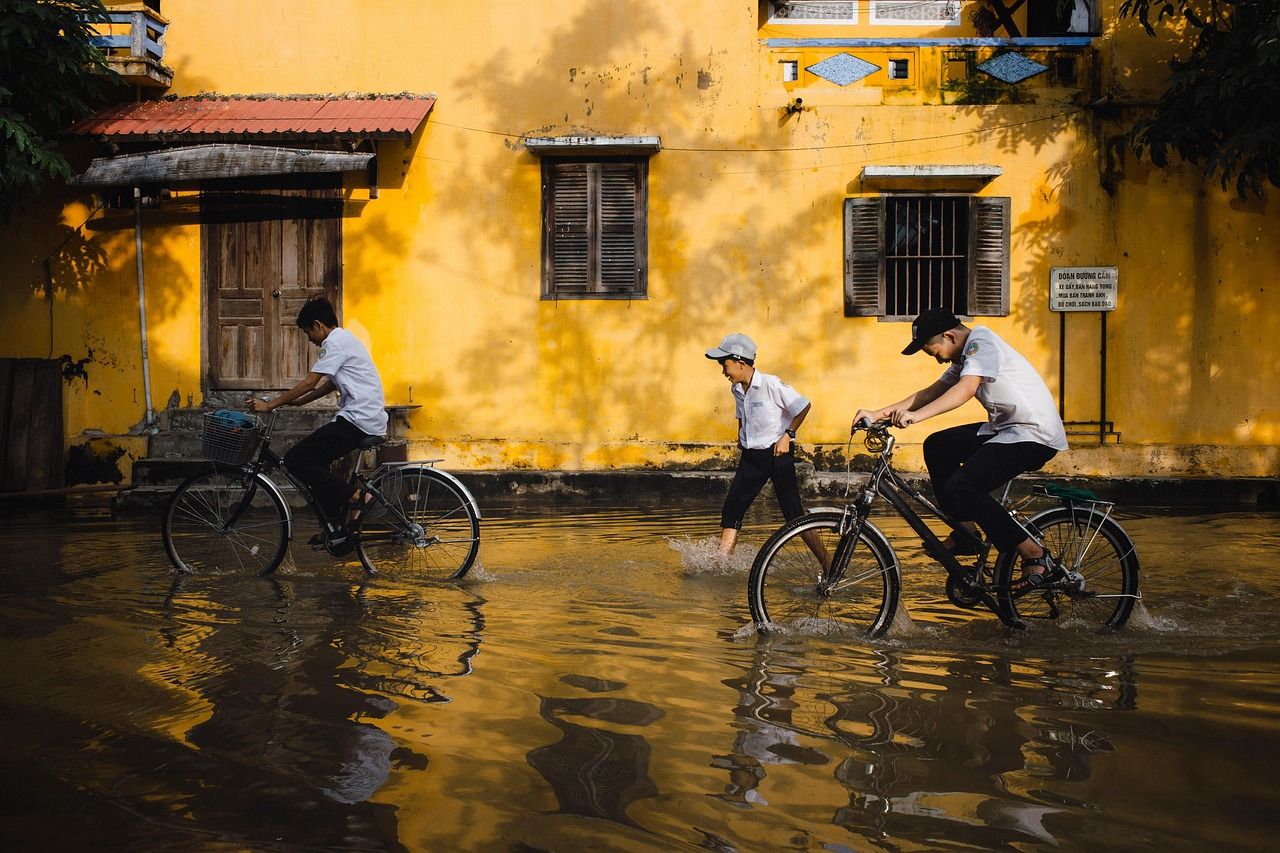 Children riding bicycles through a flooded street