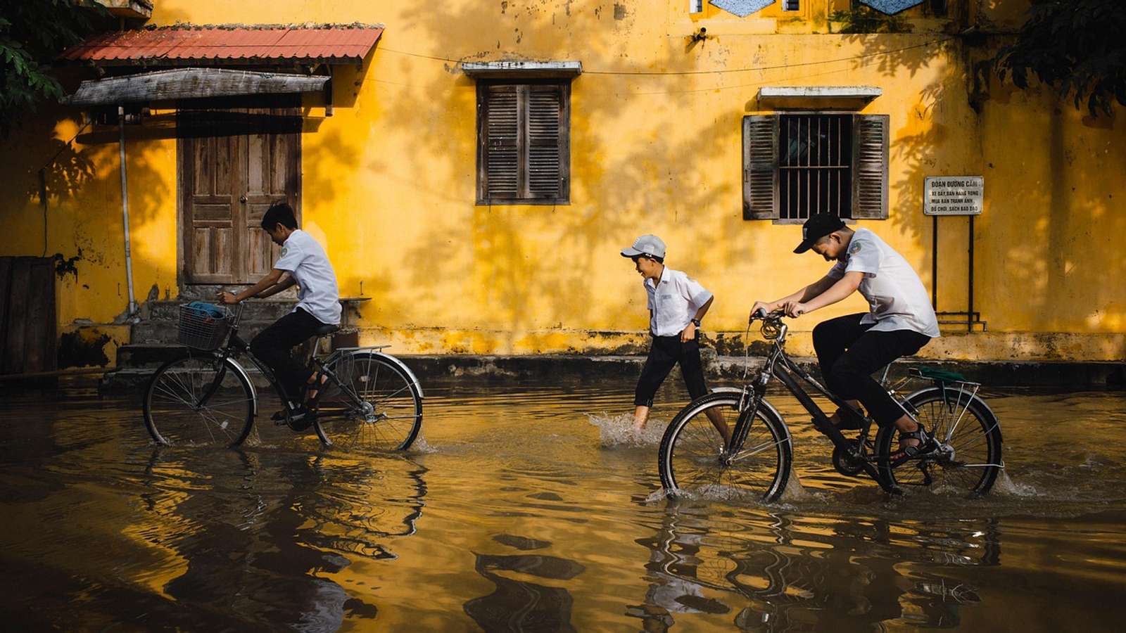 Children riding bicycles through a flooded street