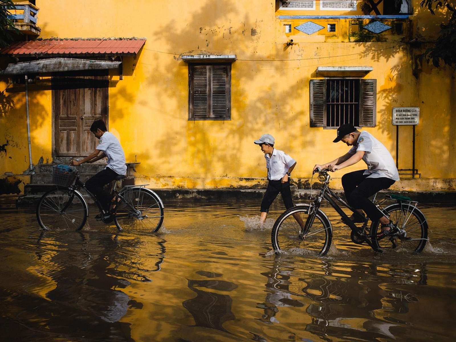 Children riding bicycles through a flooded street
