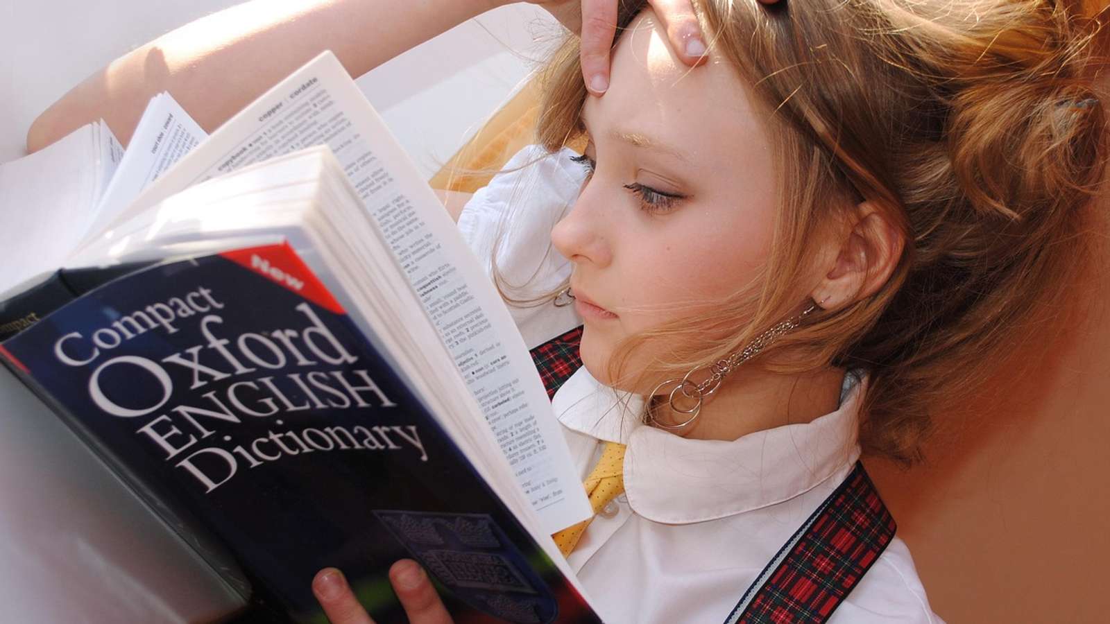 A girl studying with an open dictionary