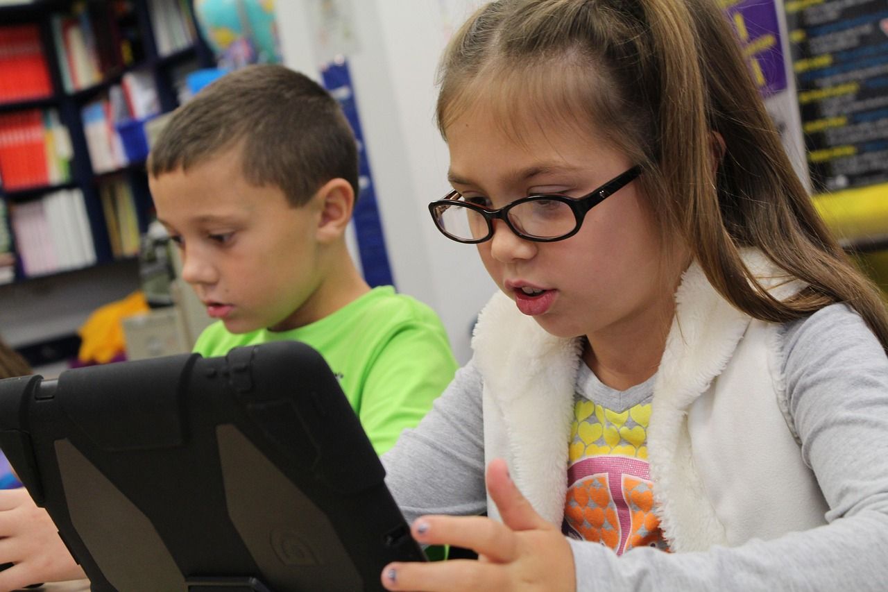 Two schoolchildren working on tablet computers in a classroom