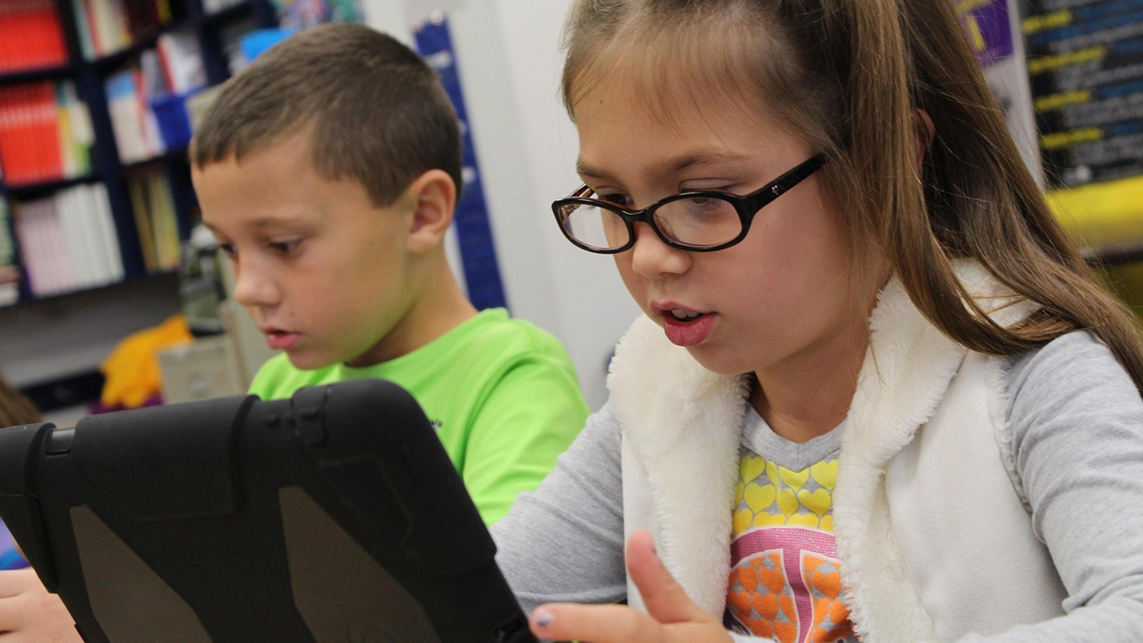 Two schoolchildren working on tablet computers in a classroom