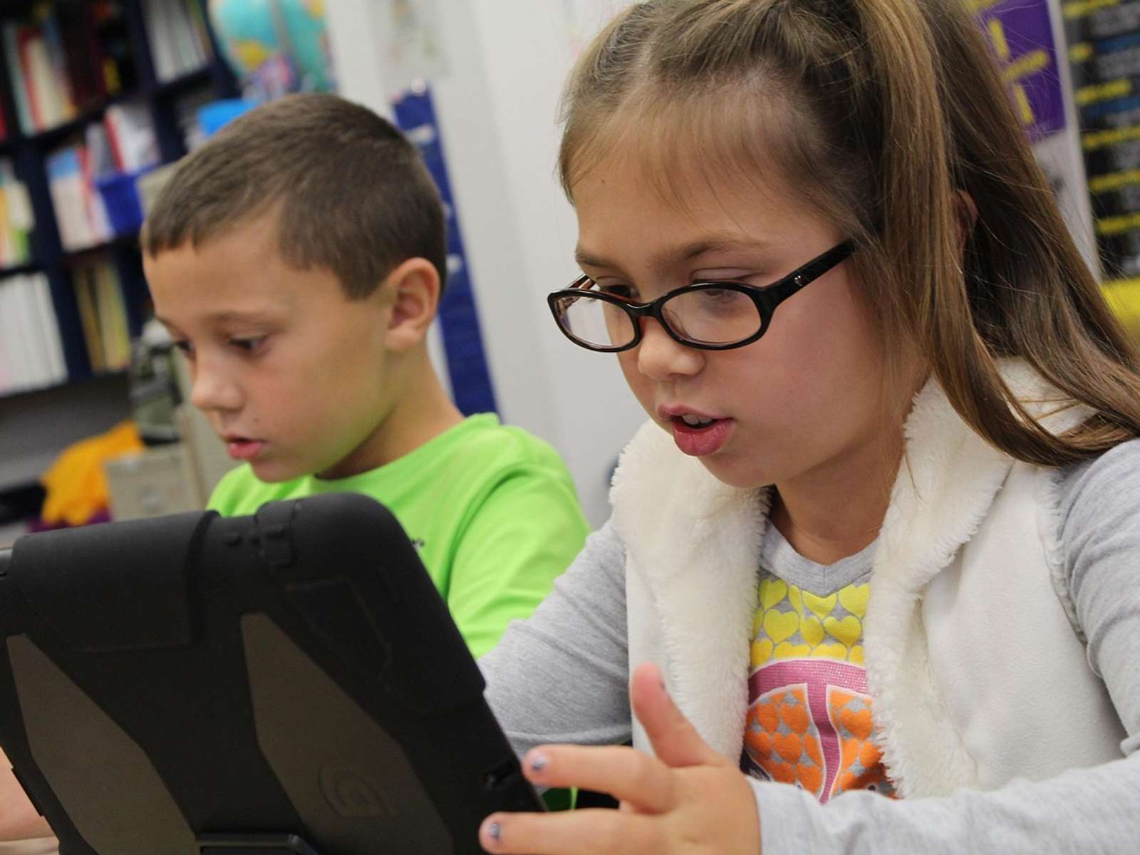 Two schoolchildren working on tablet computers in a classroom