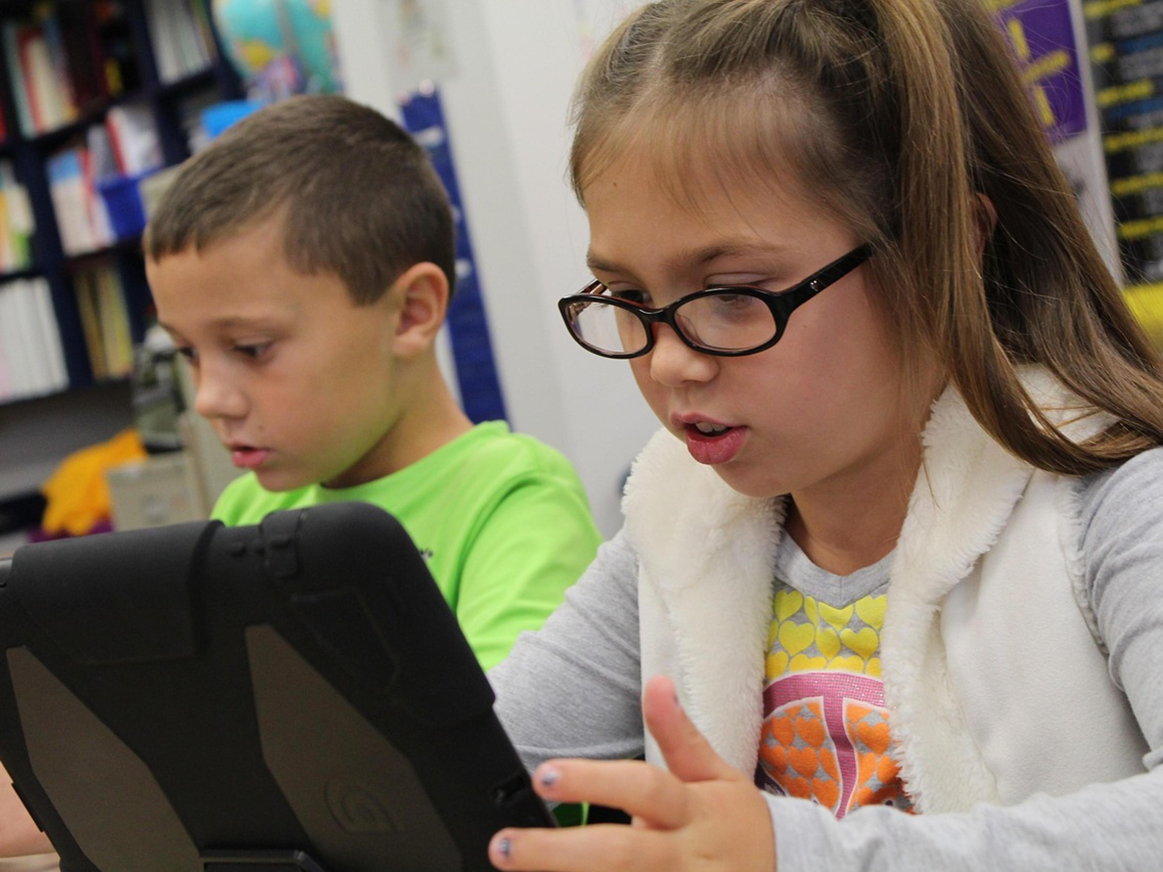 Two schoolchildren working on tablet computers in a classroom