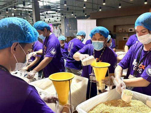 Volunteers in matching sweaters packing food donations into cardboard boxes together, working as a team indoors