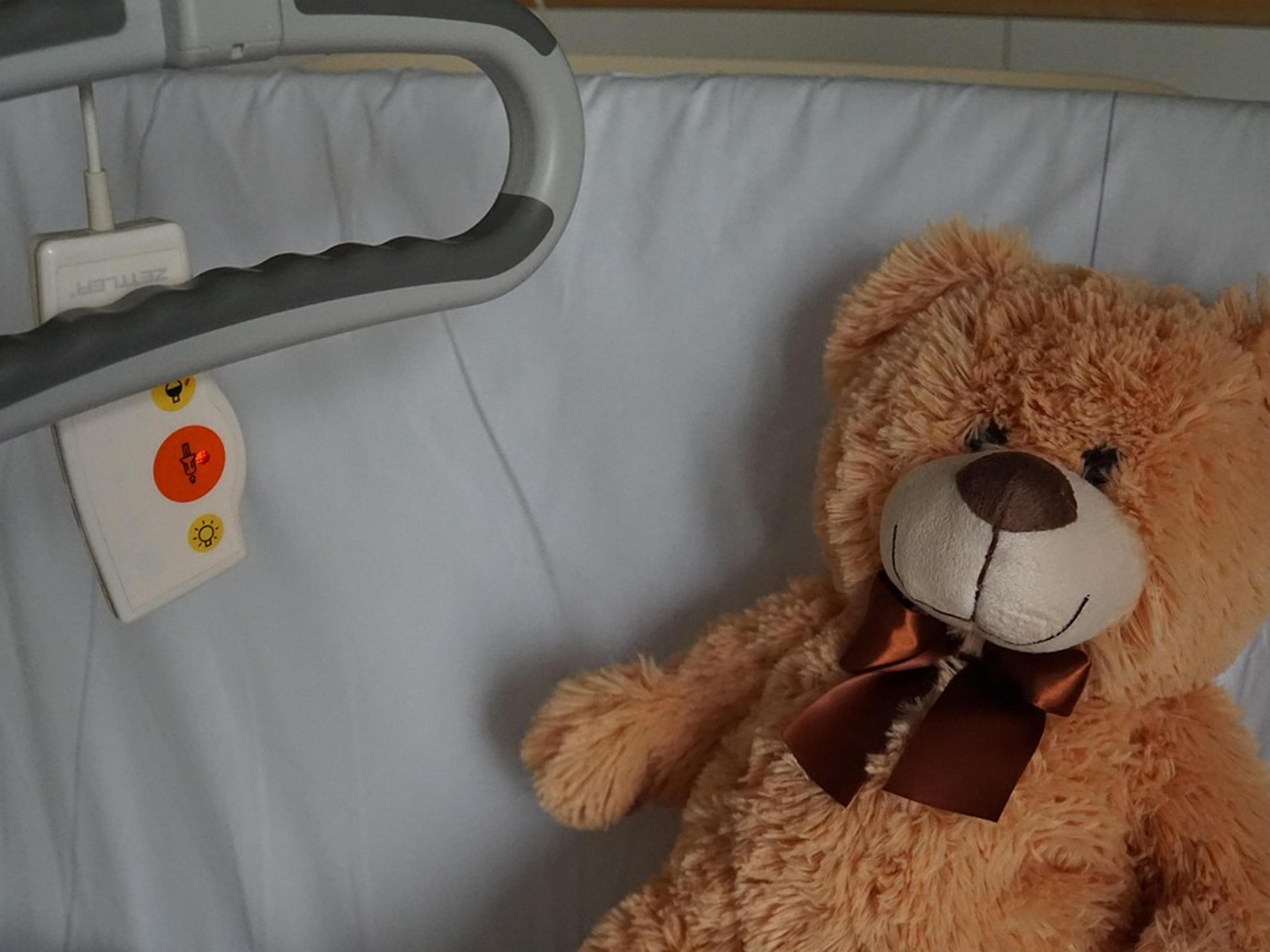 A teddy bear lying on a hospital bed
